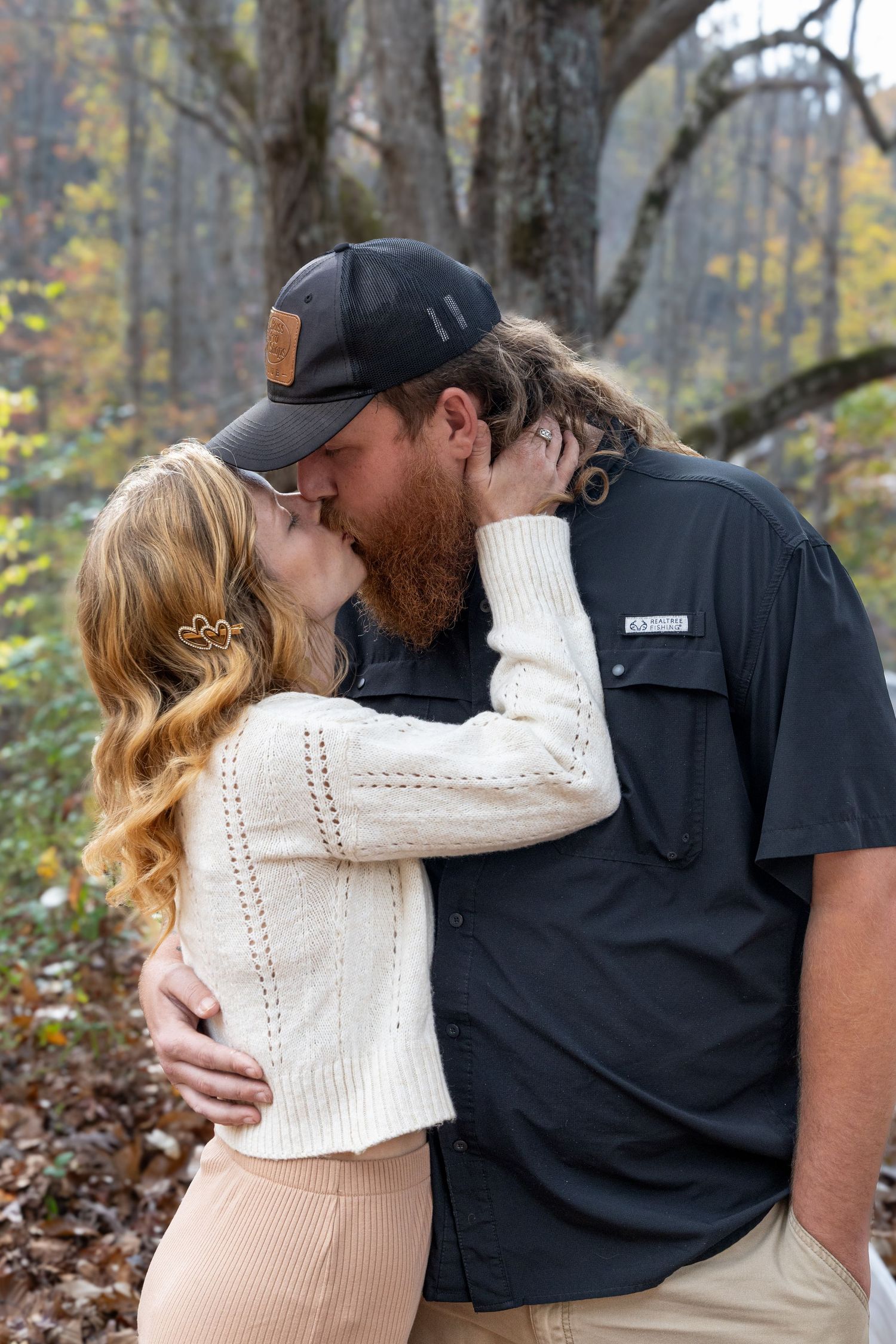 Man and woman kissing while holding each other in a beautiful forest