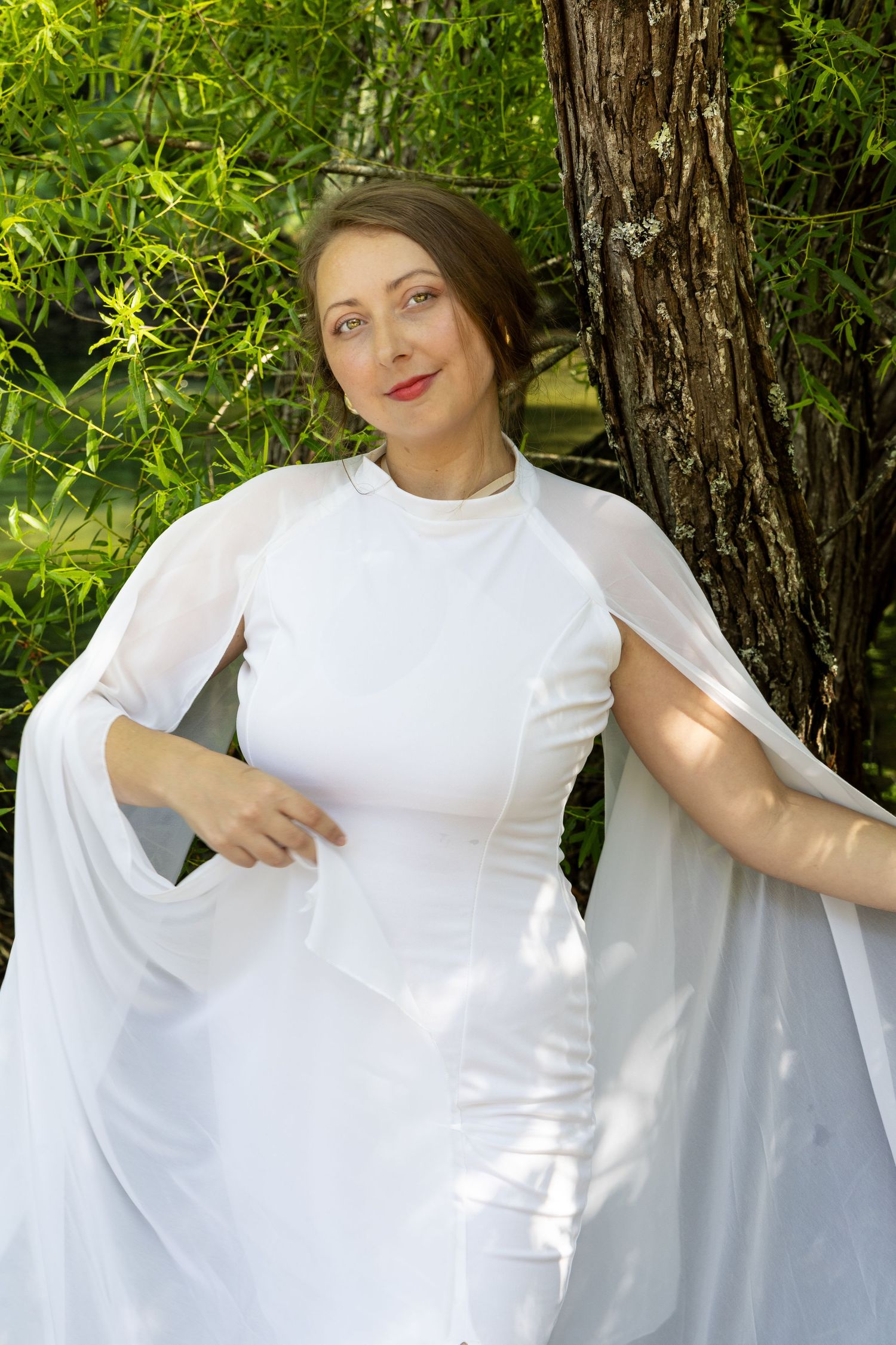 Bridal portraiture of beautiful bride in white flowy dress by the lake