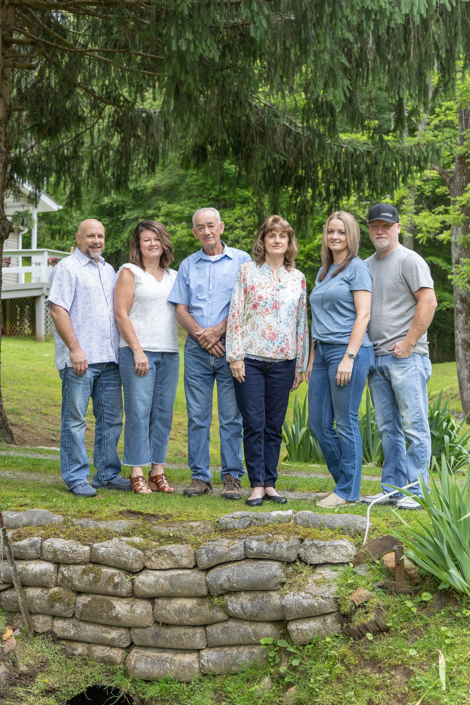 Family of multiple generations dressed in blue standing on a bridge in the forest