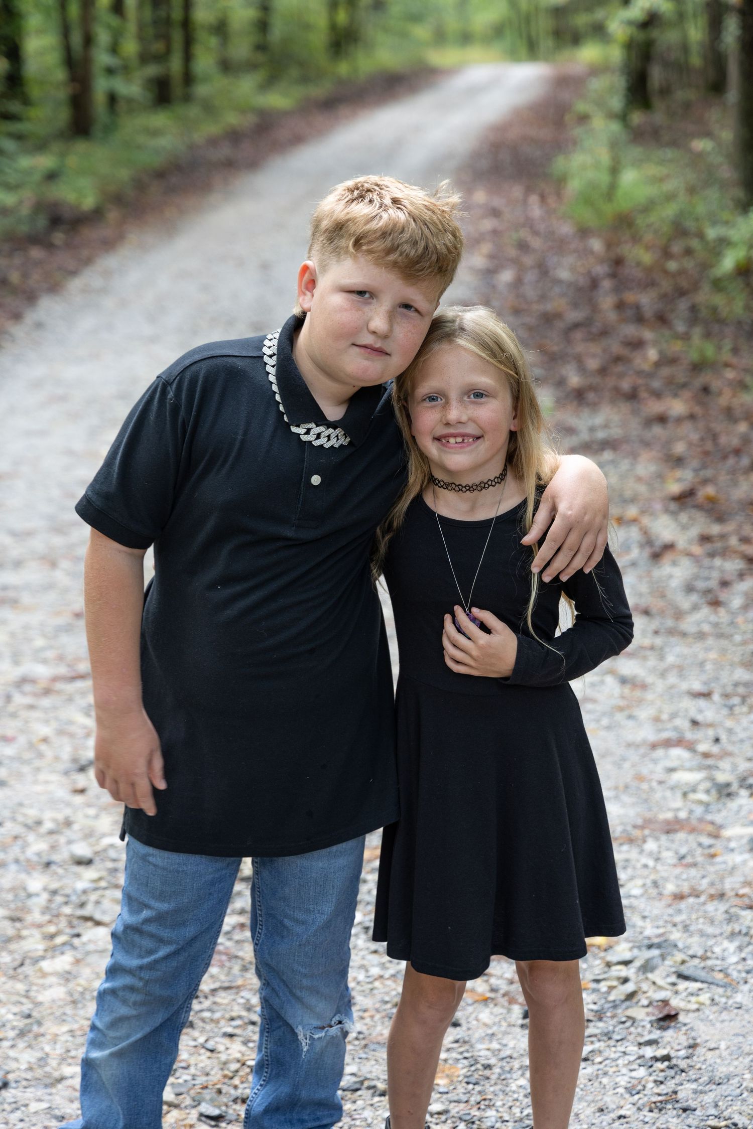 Boy and girl children taking a family photo dressed in black and in the forest