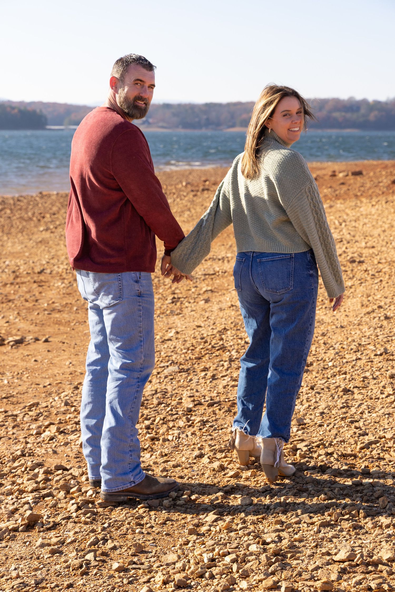 Man and woman walking on the beach of a lake holding hands