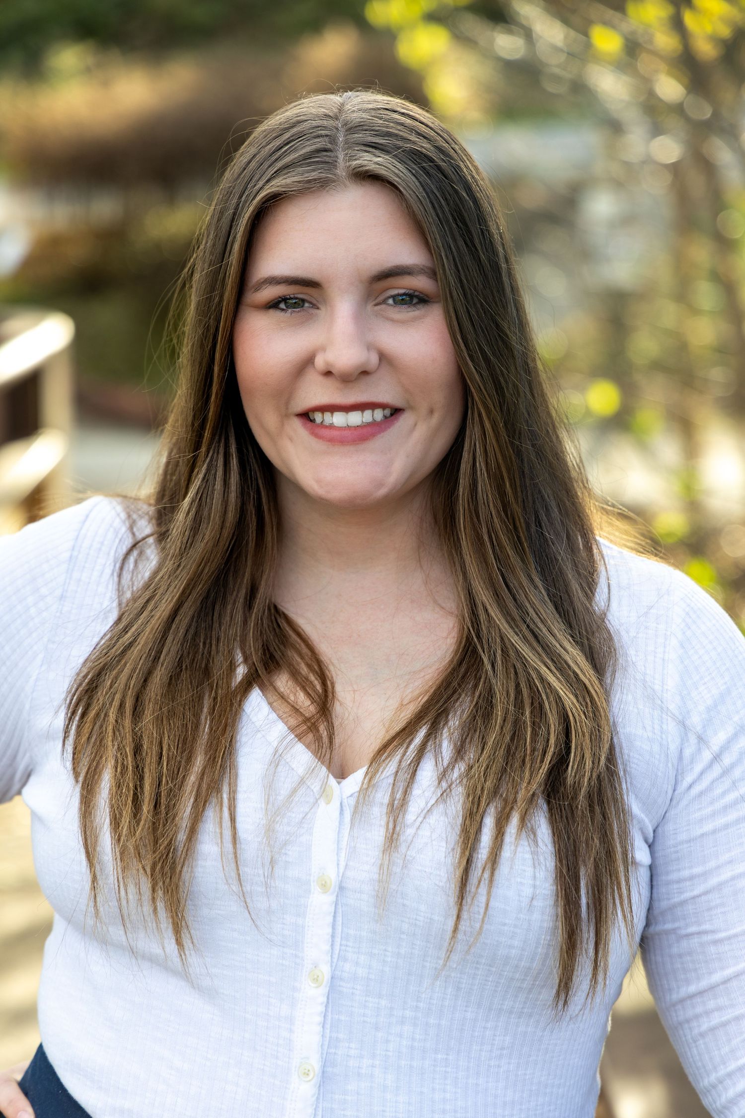 Headshot of beautiful woman with brown hair wearing a white shirt