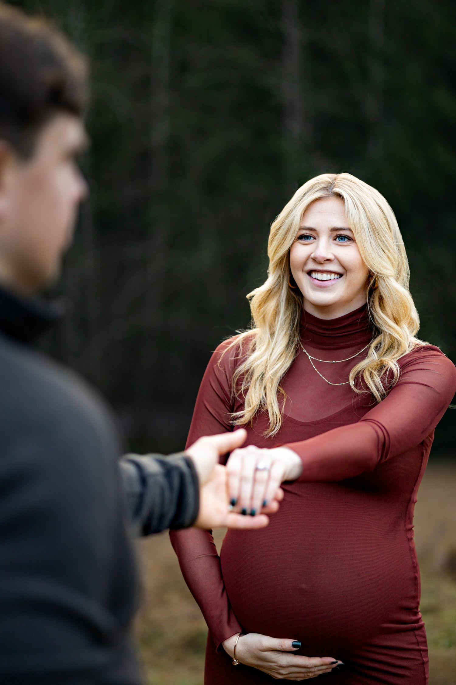 Maternity photos with emphasis on the mom. Candid maternity photo. Moody. In a field. holding hands maternity photo.