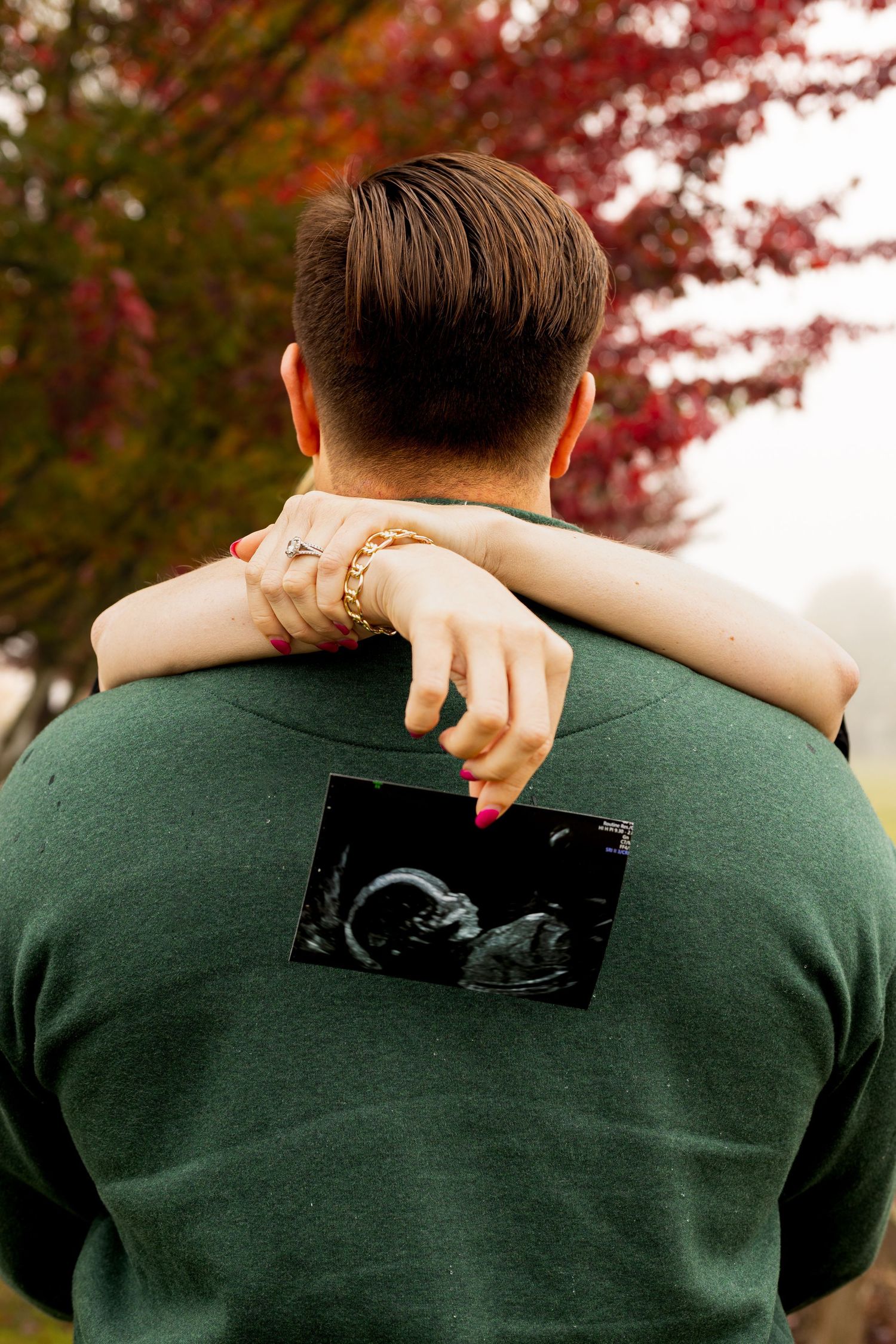 baby announcement in the fall. photo of the ultrasound. Moody. fall colors and trees in the background.