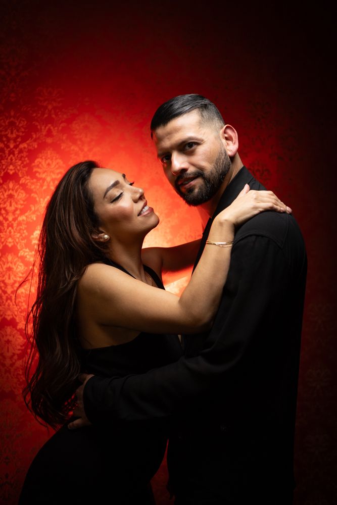 Intimate moment captured against vibrant red wall.