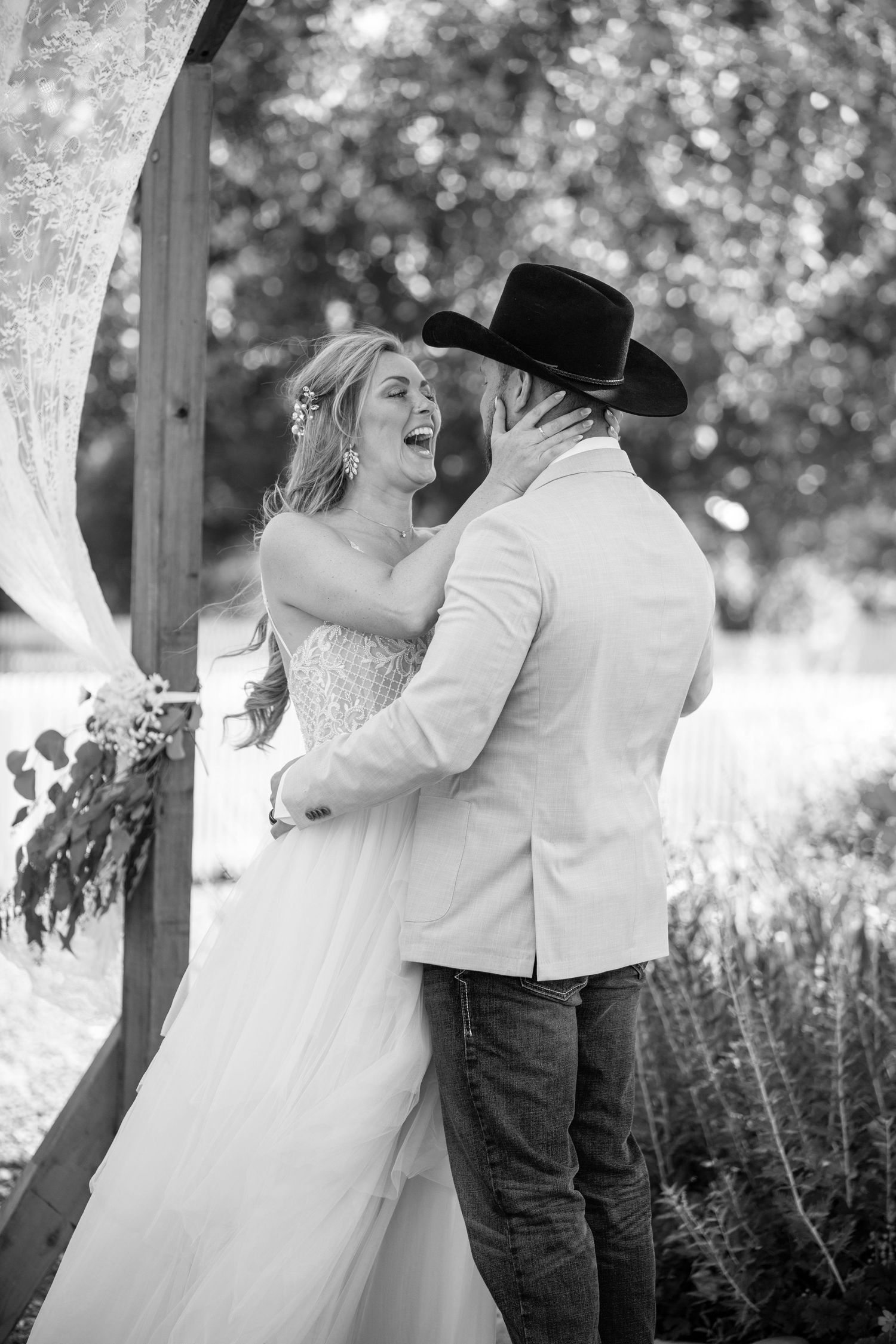 Black and white photo of a couple sharing a joyful moment among lavender flowers.