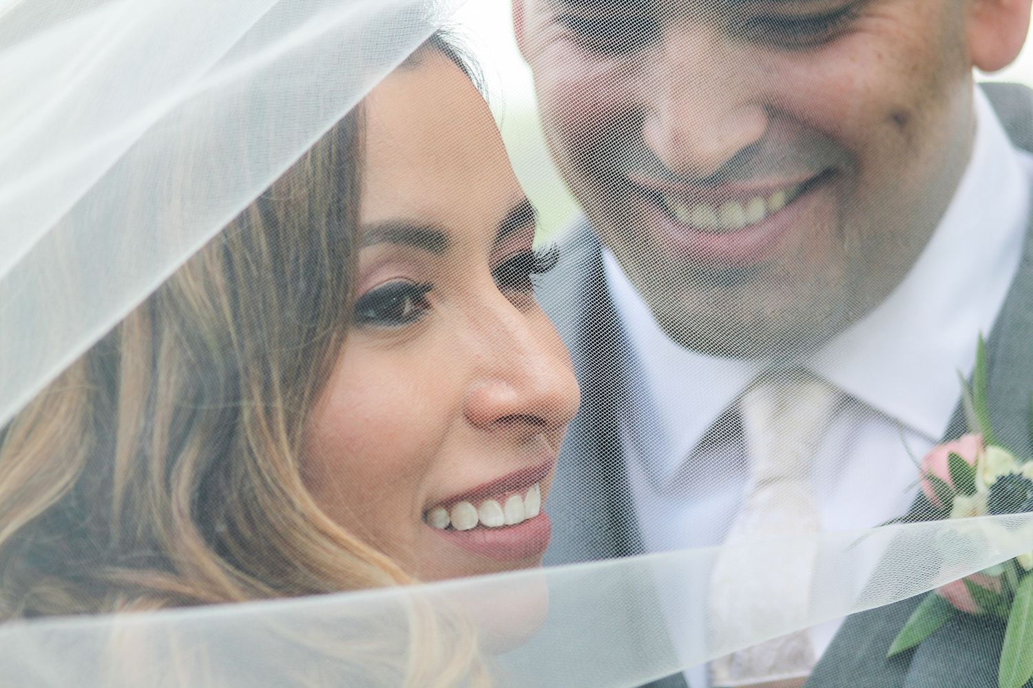 Romantic wedding couple shares tender moments under flowing white veil.