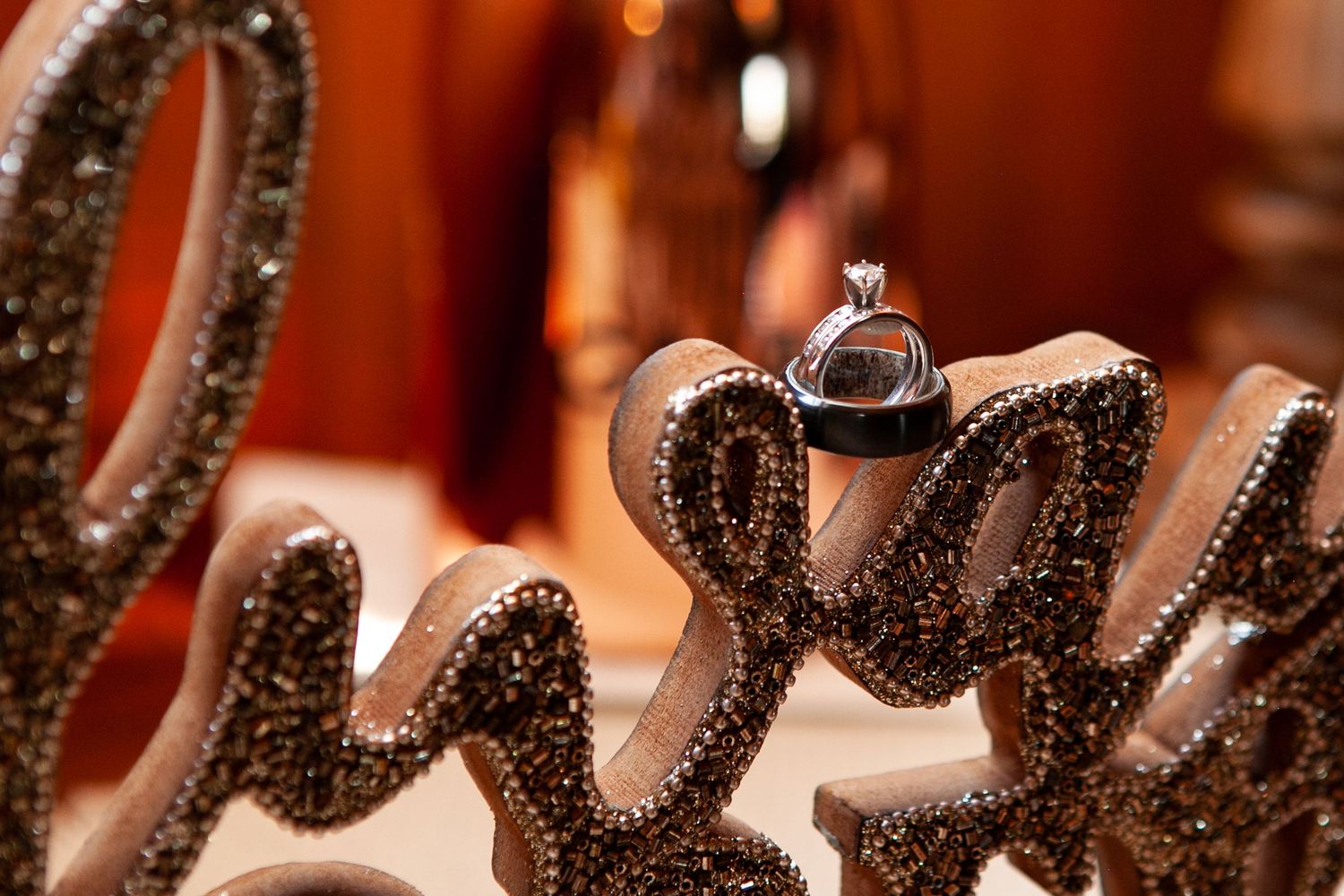 Close-up detail of wedding rings, placed in setting decor with bokeh lighting effects.
