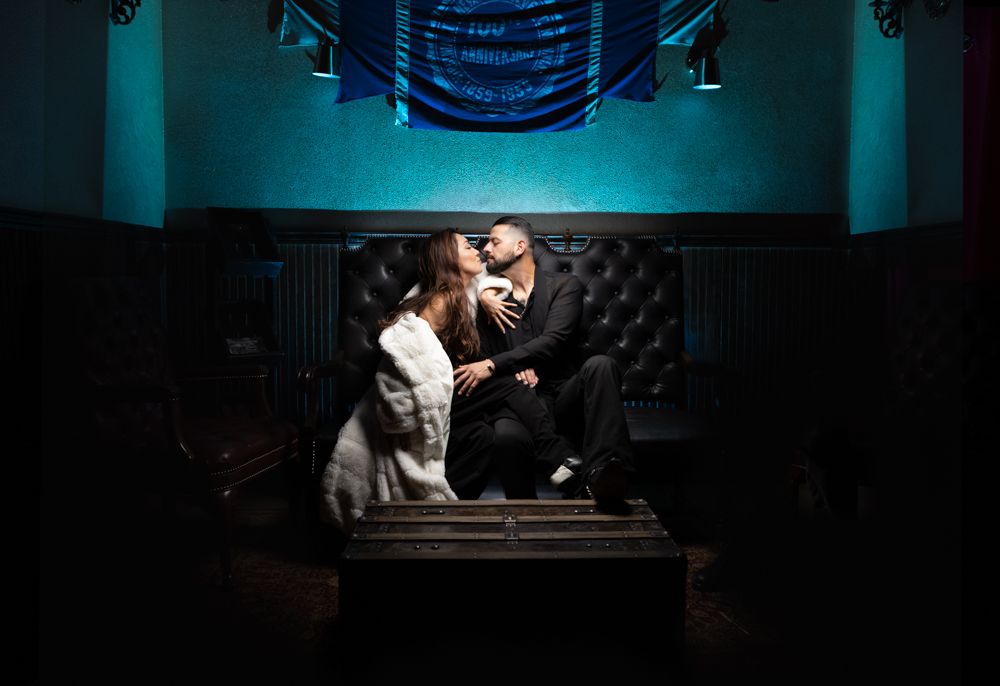 A romantic portrait with teal ambient lighting in a dark room.