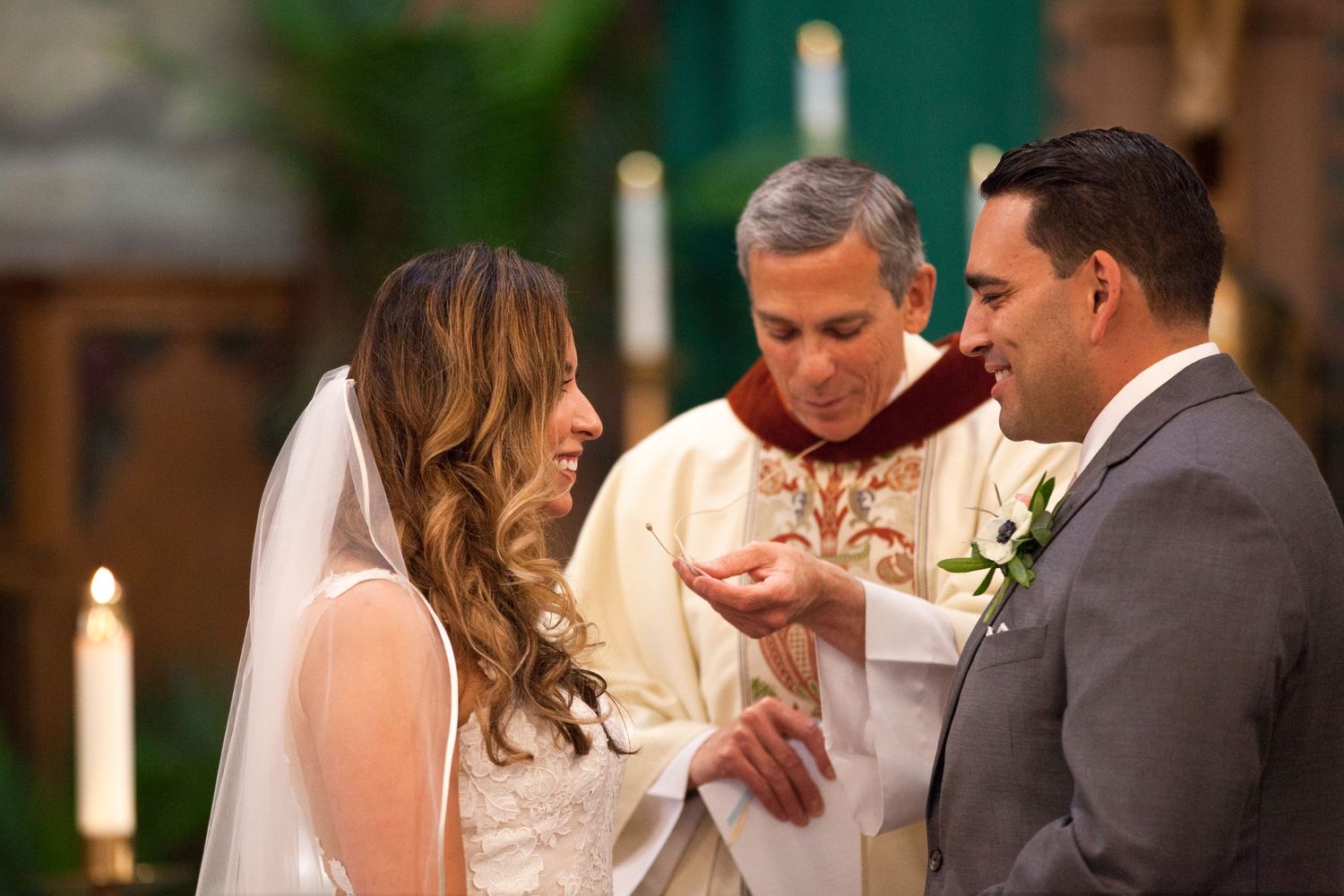 Wedding ceremony in progress at traditional church altar with lit candles.