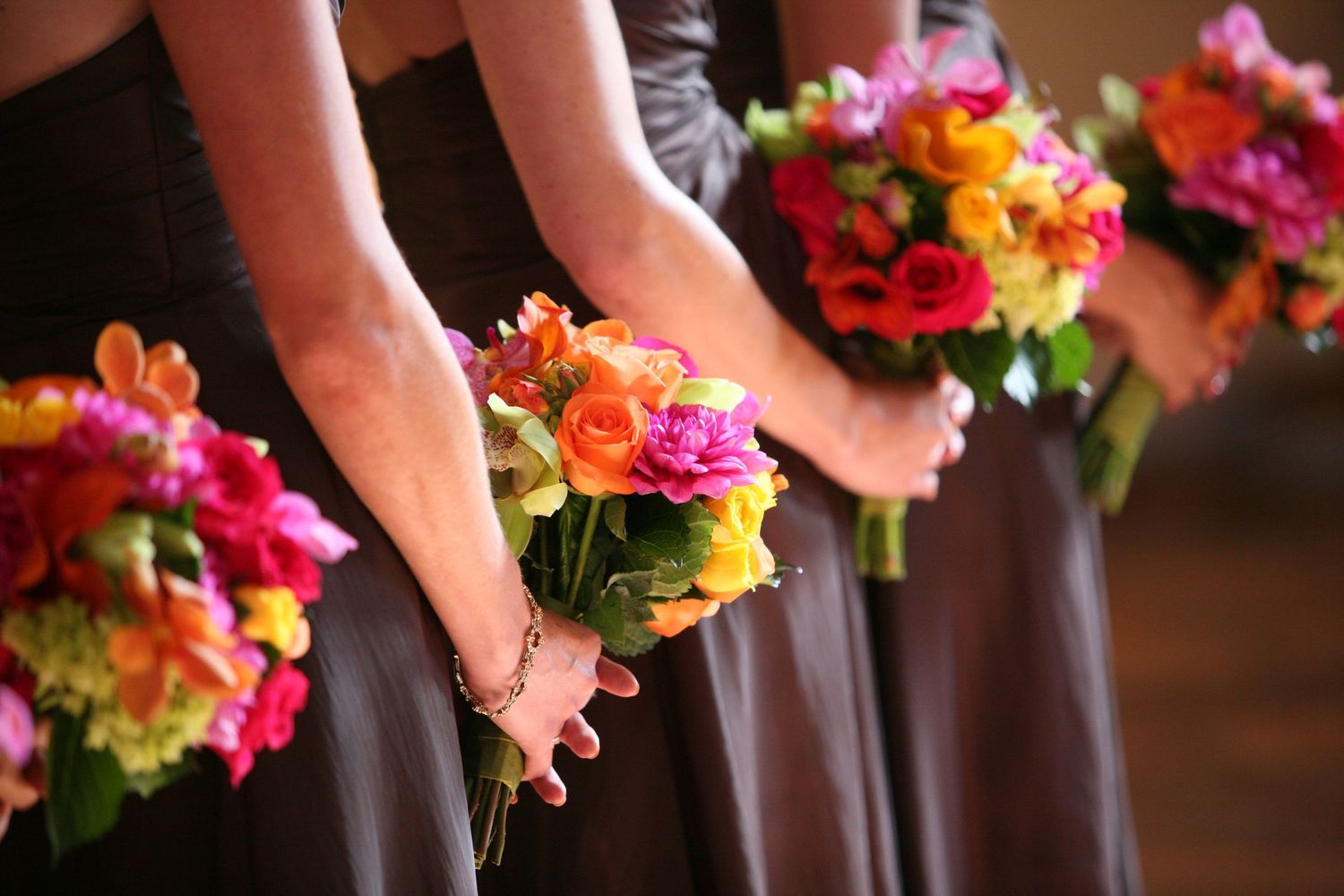 Vibrant pink and orange floral bouquets arranged in a row for a wedding celebration.