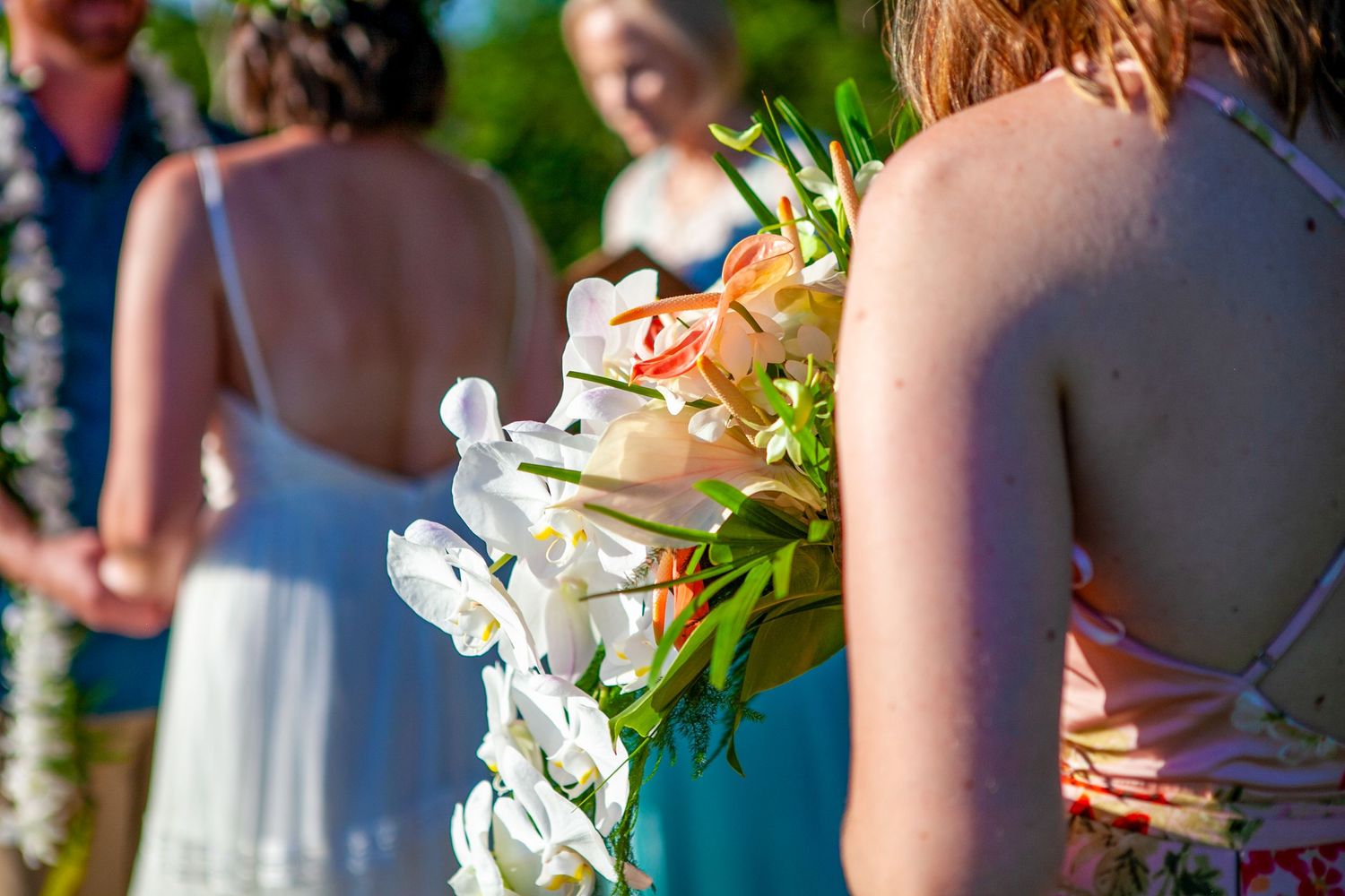 Elegant white orchid bouquets held by wedding attendees at an outdoor ceremony in Kauai.