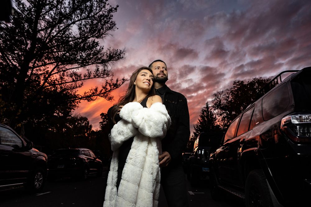 Silhouetted couple embracing against dramatic purple sunset sky.