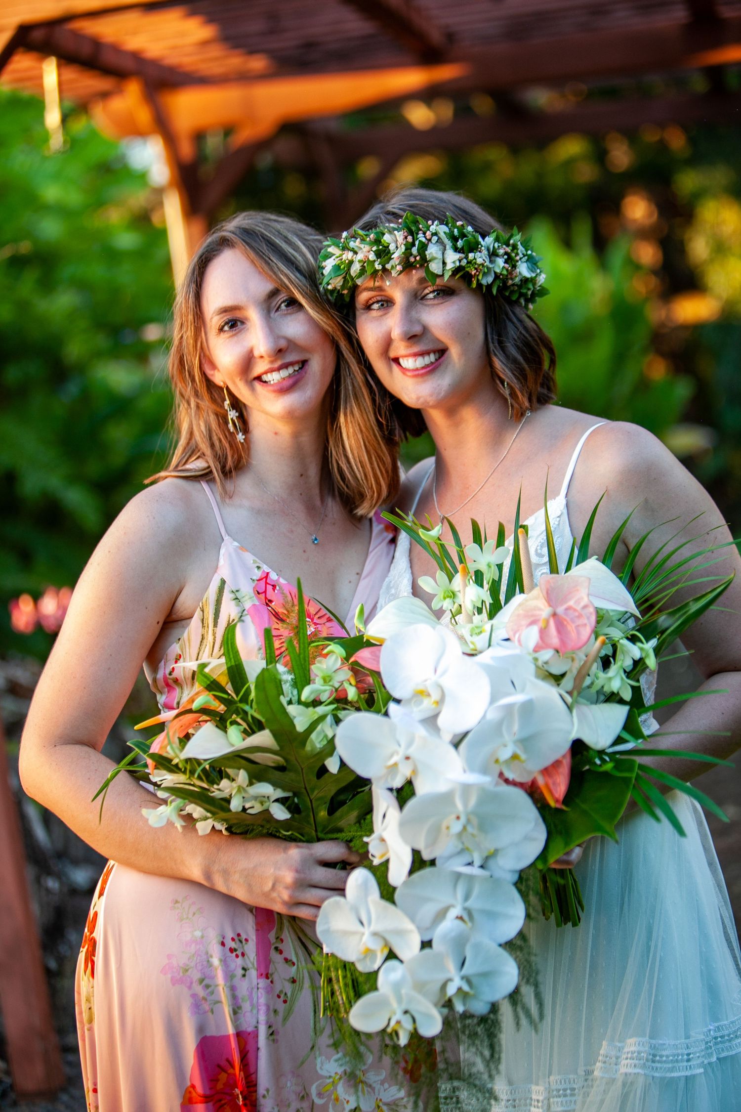 Wedding attendants holding elegant white orchid and tropical flower bouquets in garden setting in Kauai.