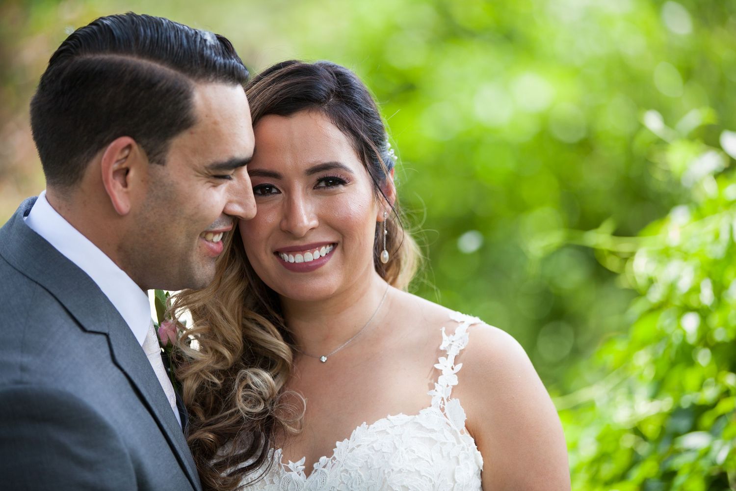 Joyful newlyweds share loving glances in a sunlit garden setting.