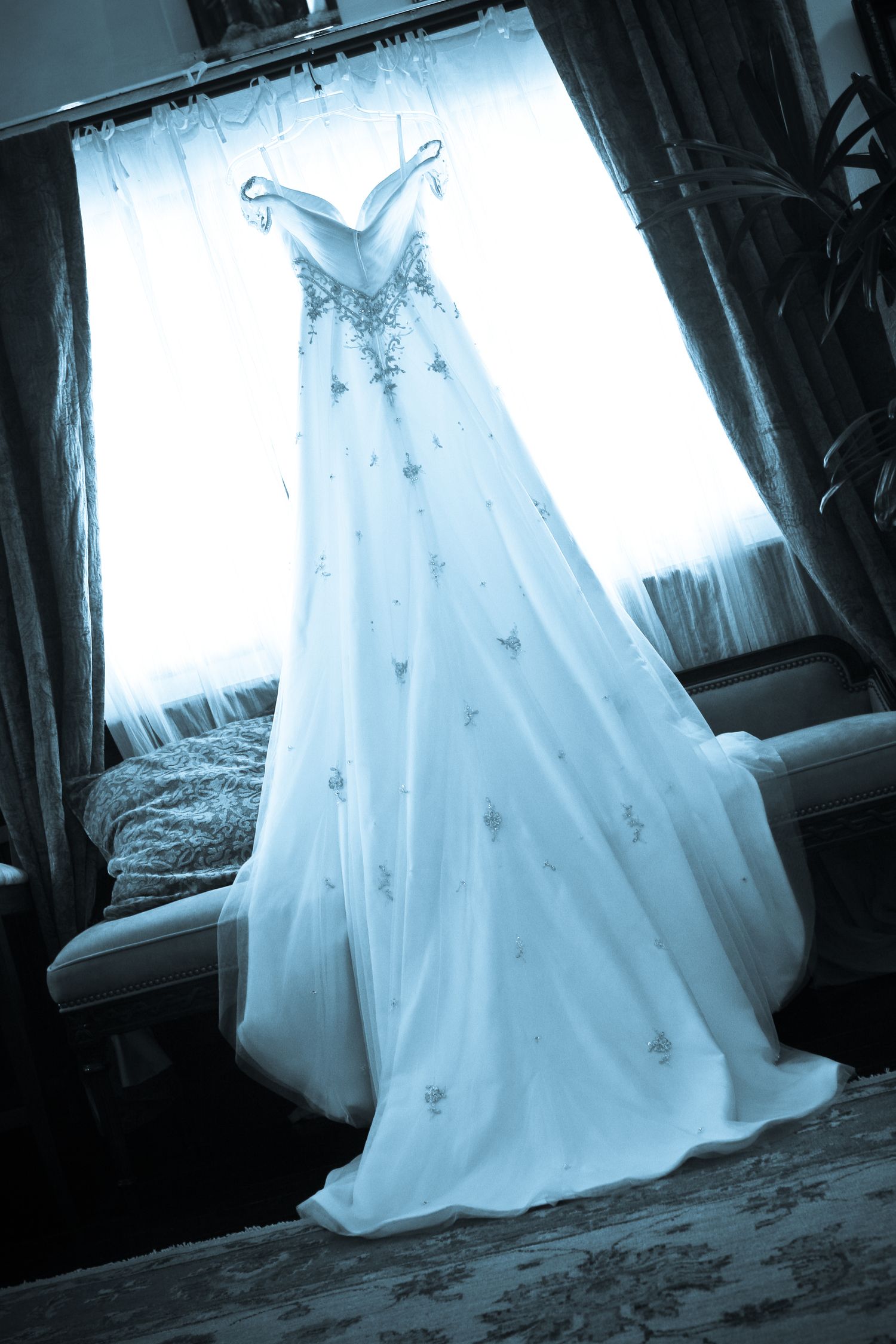 Ethereal white wedding dress photographed in dramatic lighting creating a dreamy silhouette.