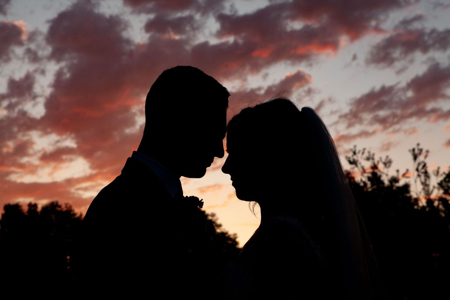 Dramatic silhouettes against vibrant red sunset sky with clouds.