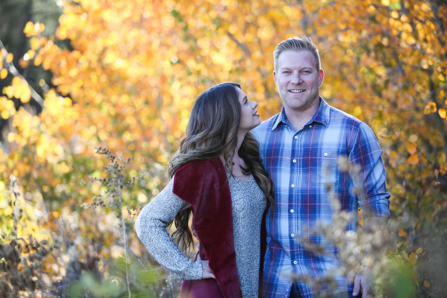 Couple shares intimate moment against vibrant autumn foliage background.