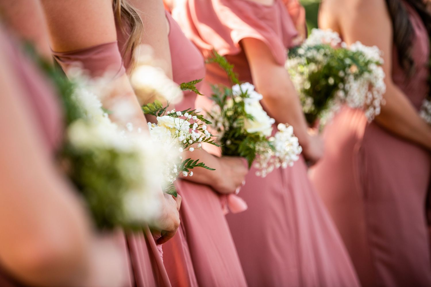 Close-up detail of pink bridesmaid dresses and white floral bouquets.