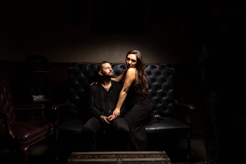 A dramatic portrait in dark lighting on a leather couch.