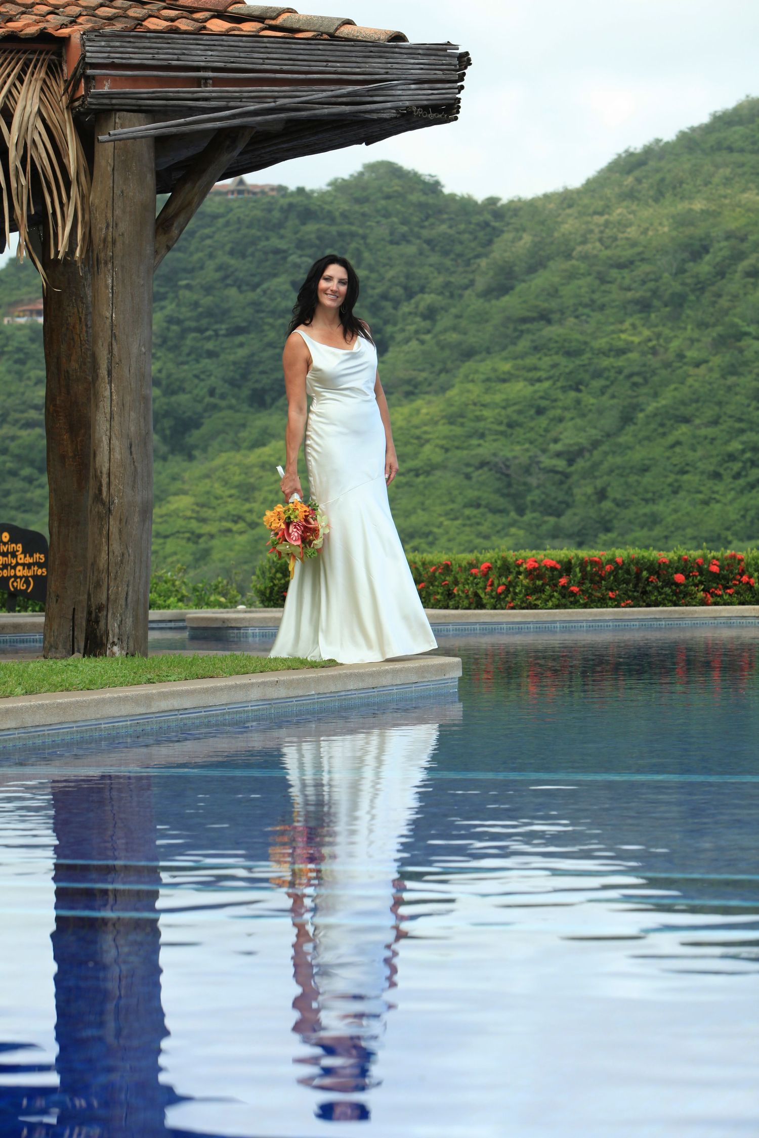 Wedding dress reflection in infinity pool overlooking tropical Costa Rica mountain landscape.