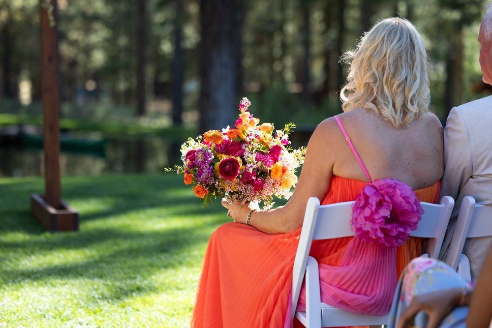 Bridesmaids in coral and pink dresses walking together outdoors.