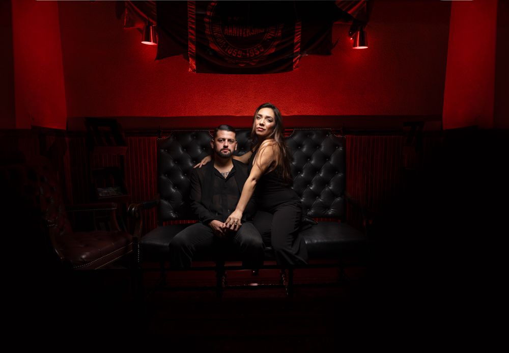 A moody portrait session in a dark room with red ambient lighting.