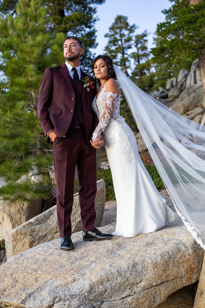 Elegant wedding couple embracing on granite rocks with pine trees in background in Heavenly Mountain resort Lake Tahoe..