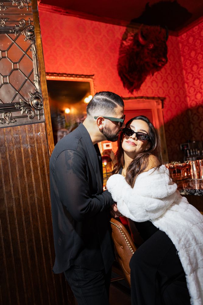 A couple shares an intimate moment in a dimly lit room with red wallpaper.