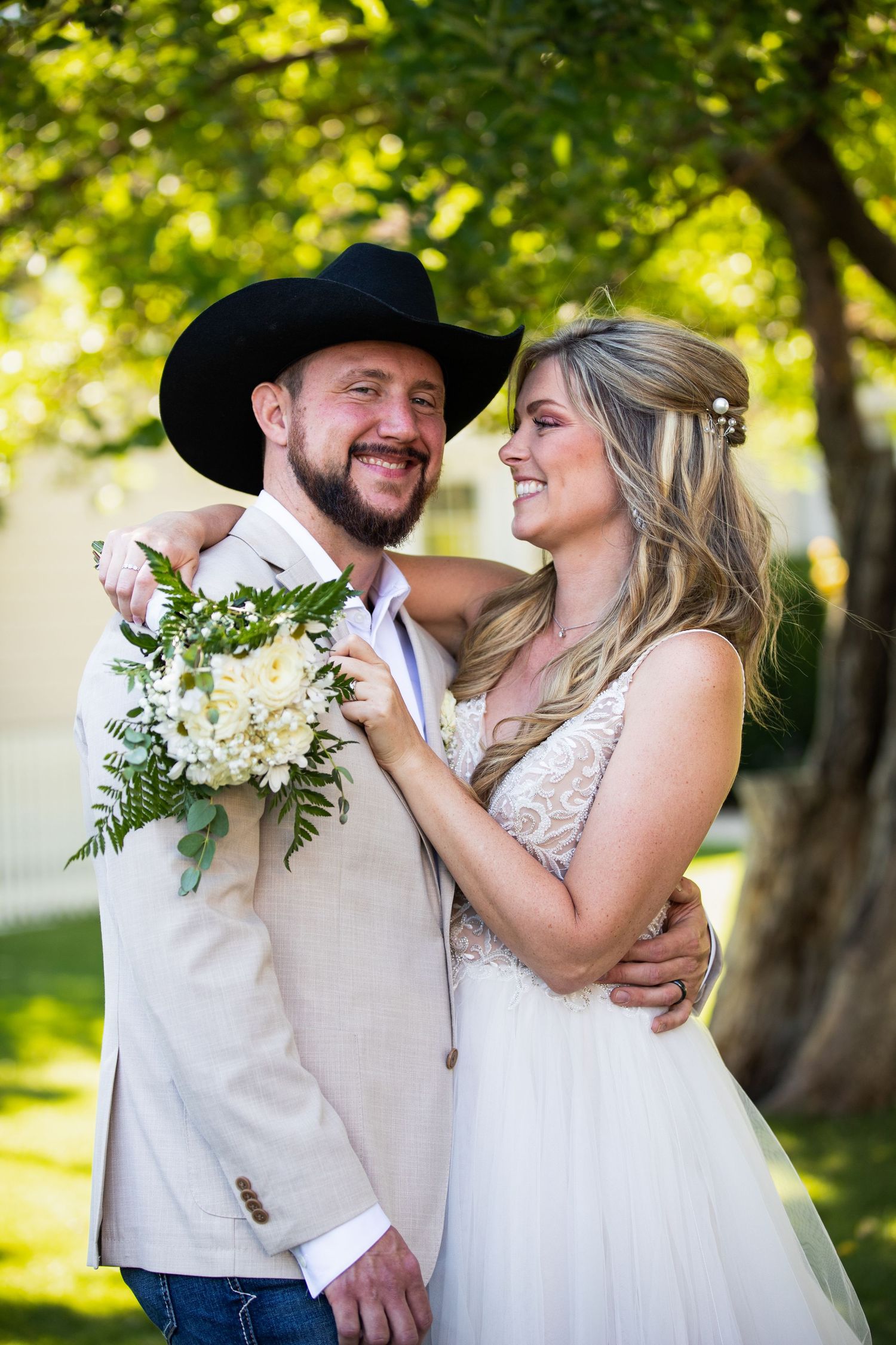 Romantic wedding couple shares intimate moments in a sunlit garden setting with white floral bouquet.