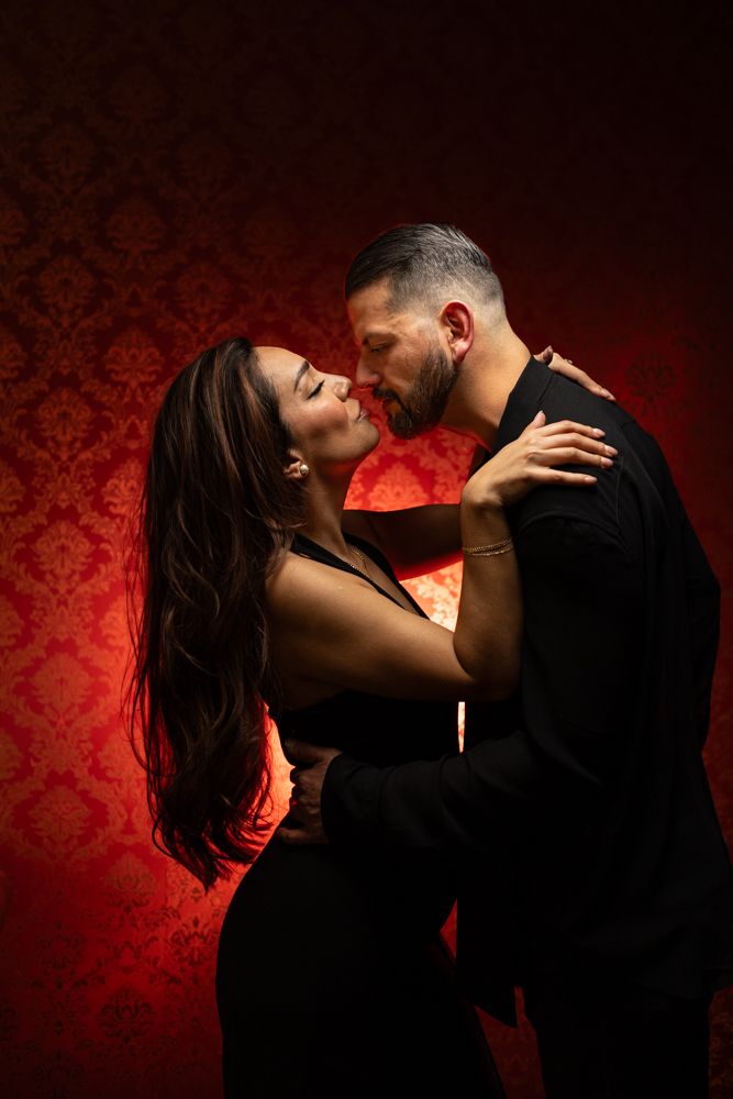 Passionate couple posed silhouetted against deep red background.