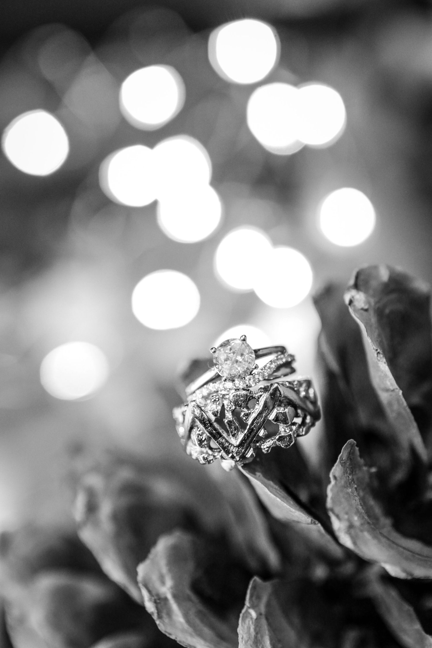Macro shot of diamond engagement ring with bokeh lights in black and white.