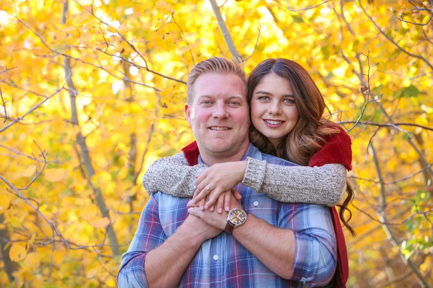 Romantic embrace captured in front of bright yellow fall foliage.