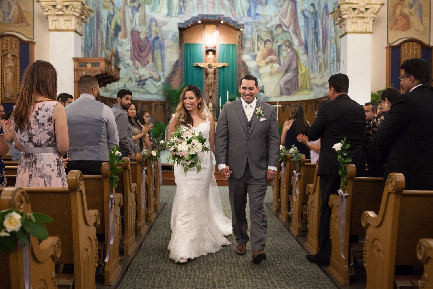 Church wedding ceremony with decorated altar and painted murals in background.