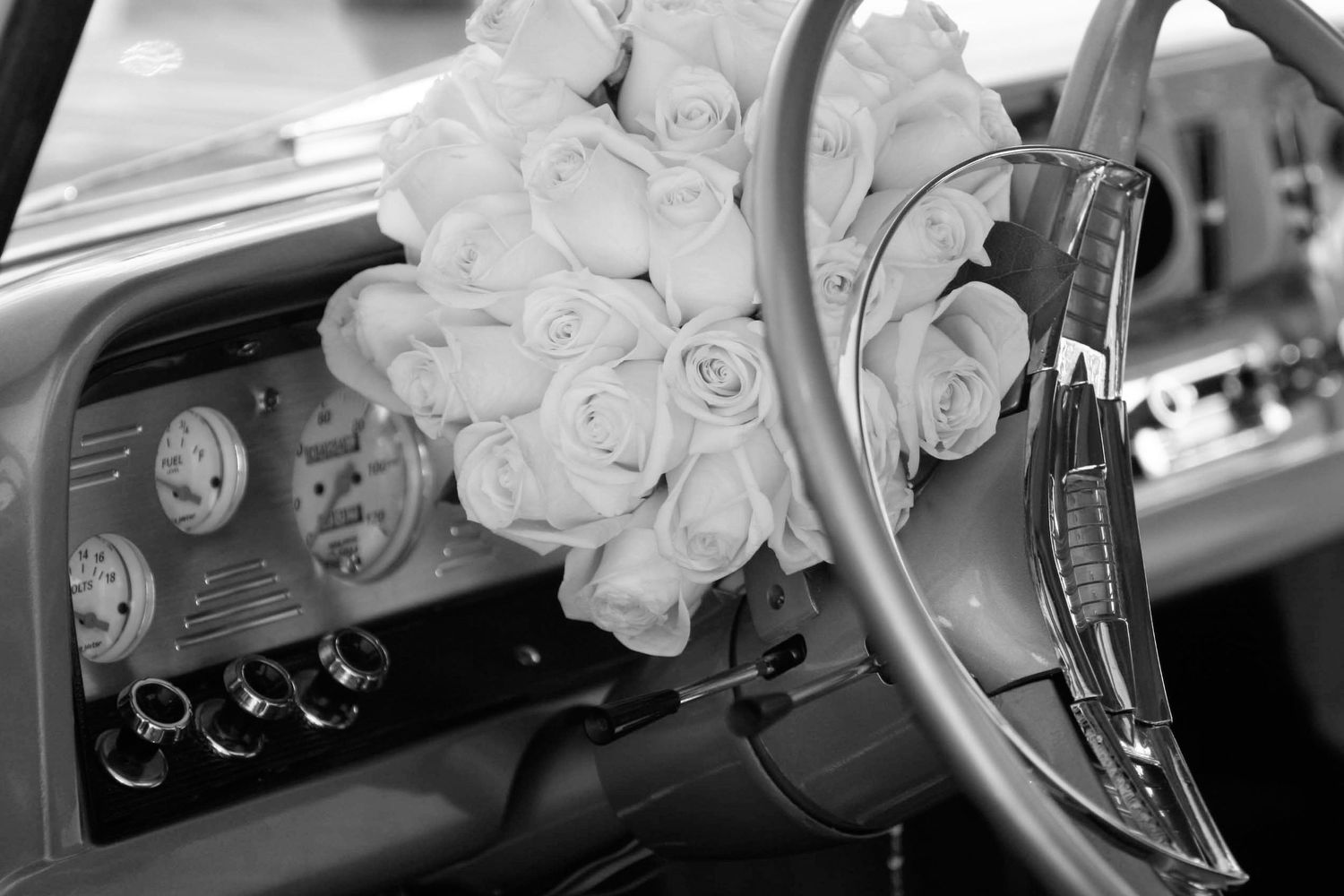 A black and white wedding photo showing hands exchanging rings during a ceremony.