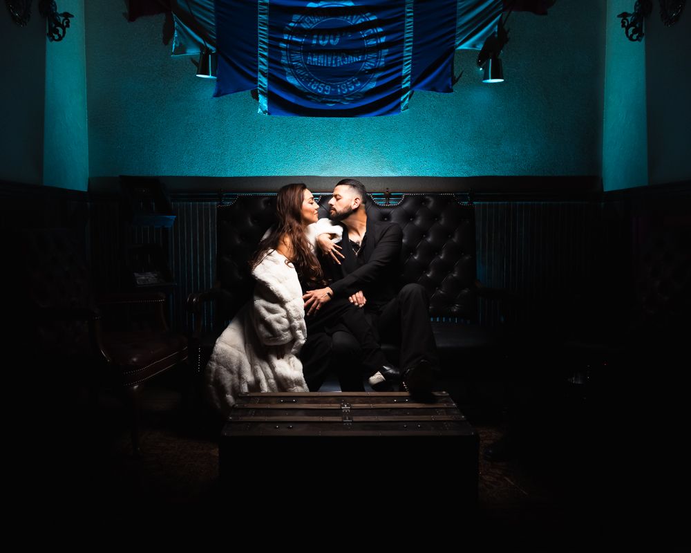 Couple sitting intimately in a dark room with dramatic lighting.