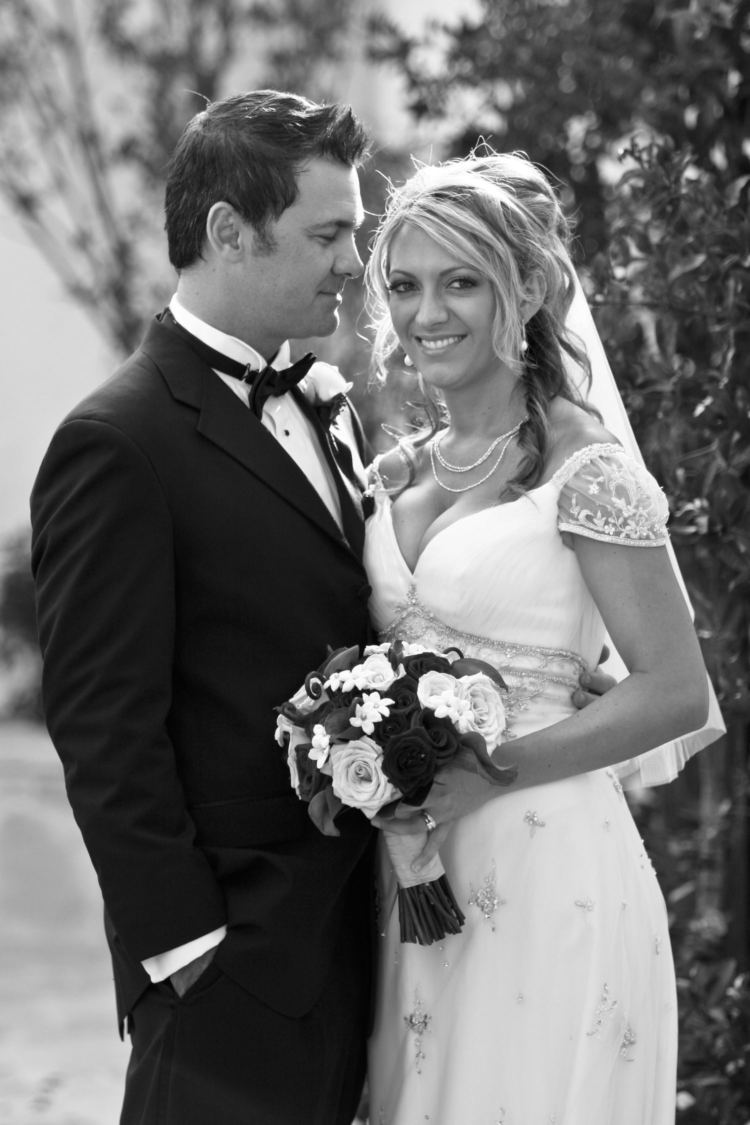 A black and white wedding portrait showing an intimate moment between newlyweds.
