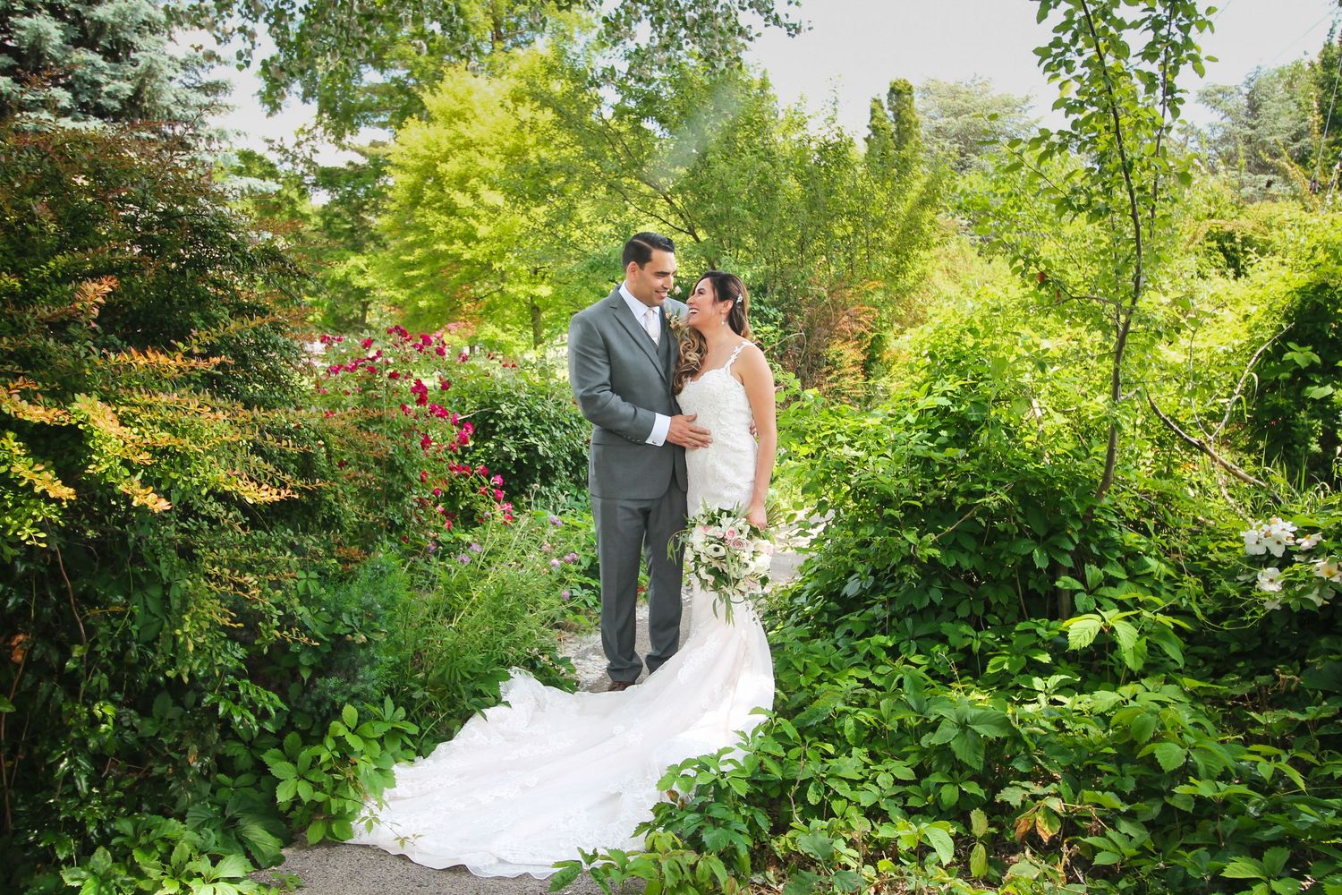 A romantic wedding couple shares intimate moments in a lush garden setting with vibrant greenery.