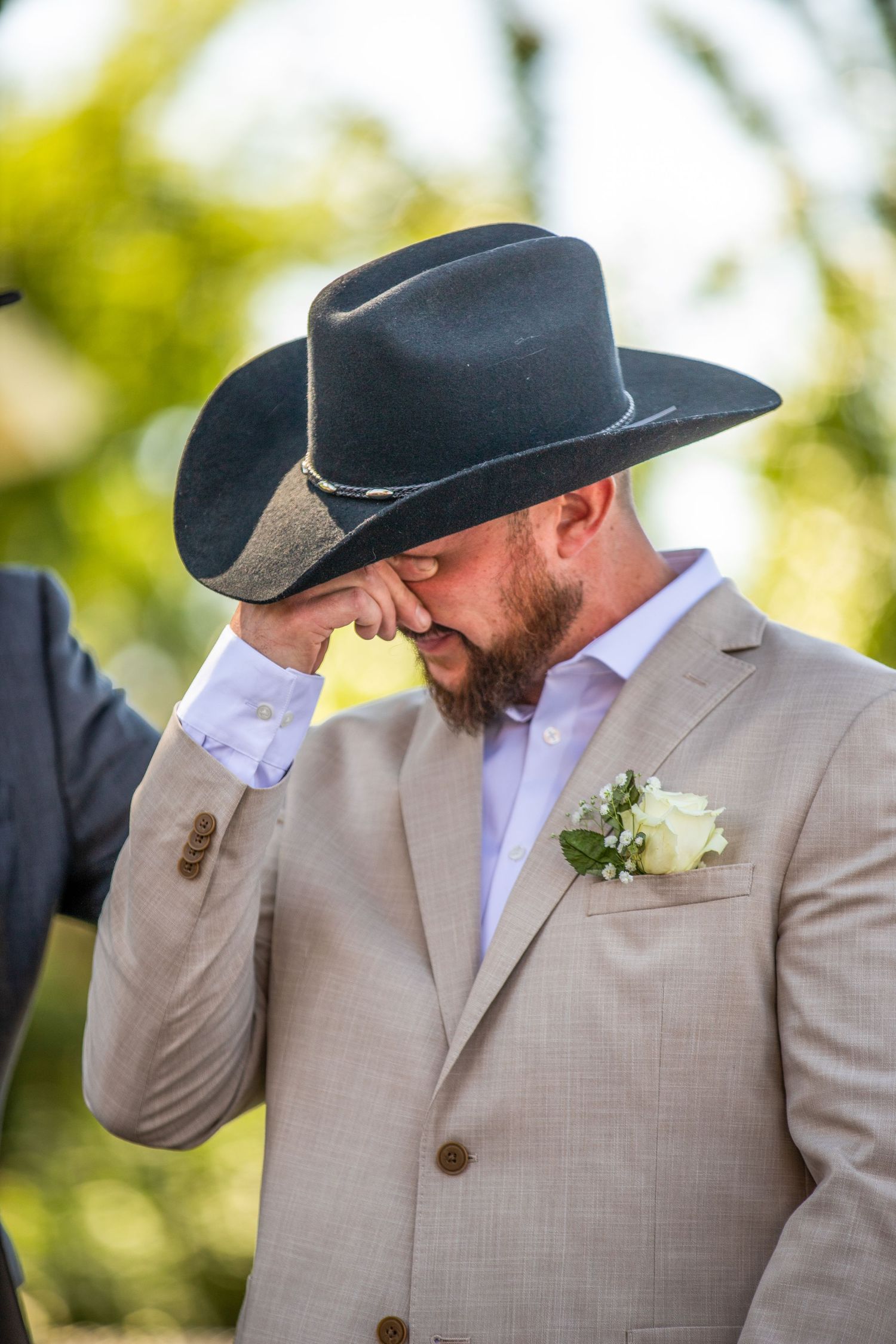 Groomsmen in tan suits and black cowboy hats share an emotional moment.