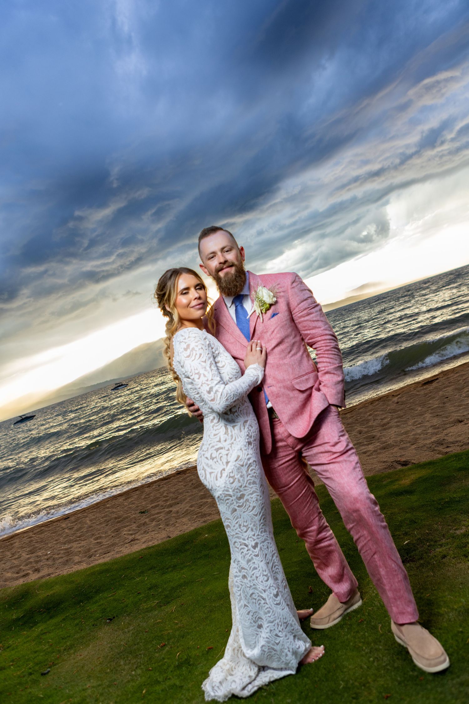 A beachside wedding portrait with dramatic stormy sky and sunset over the water.