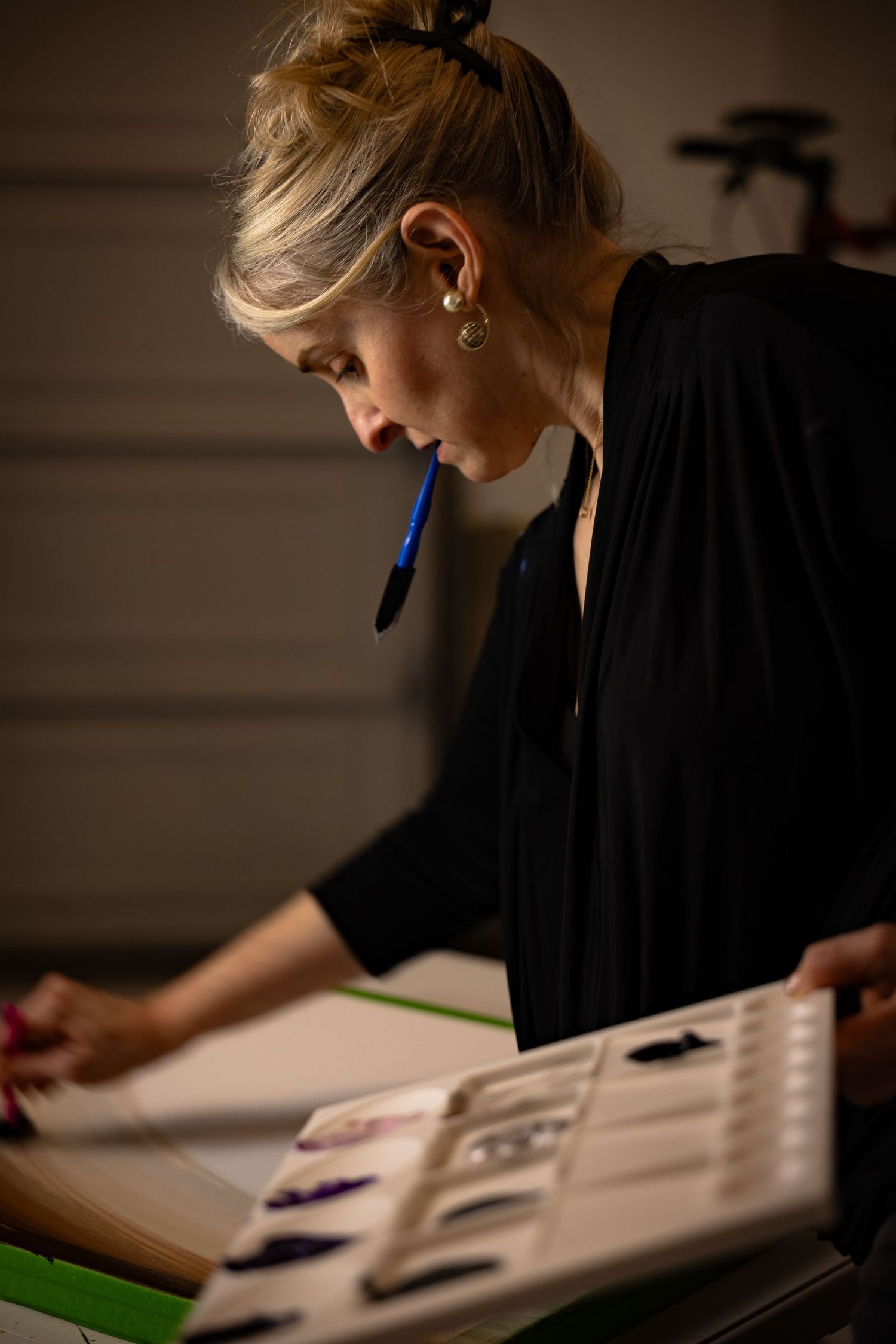 Brand photography of artist focused on creating in a dramatic light scene.