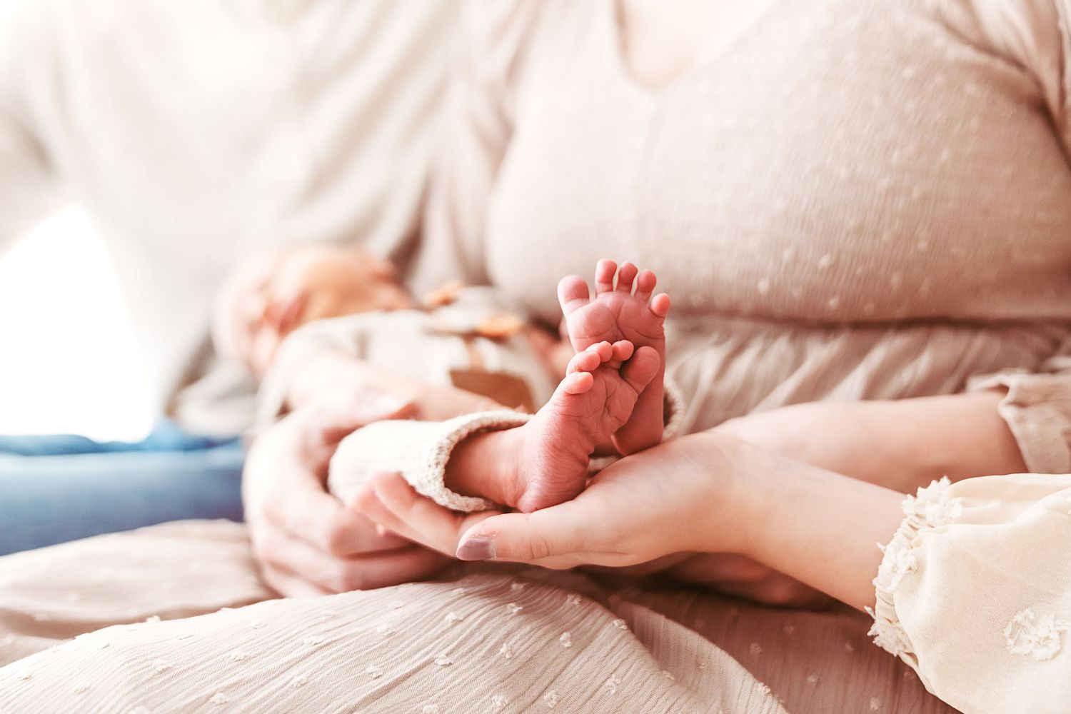 Mother gently holding tiny newborn baby feet in her hands during a newborn photography session.