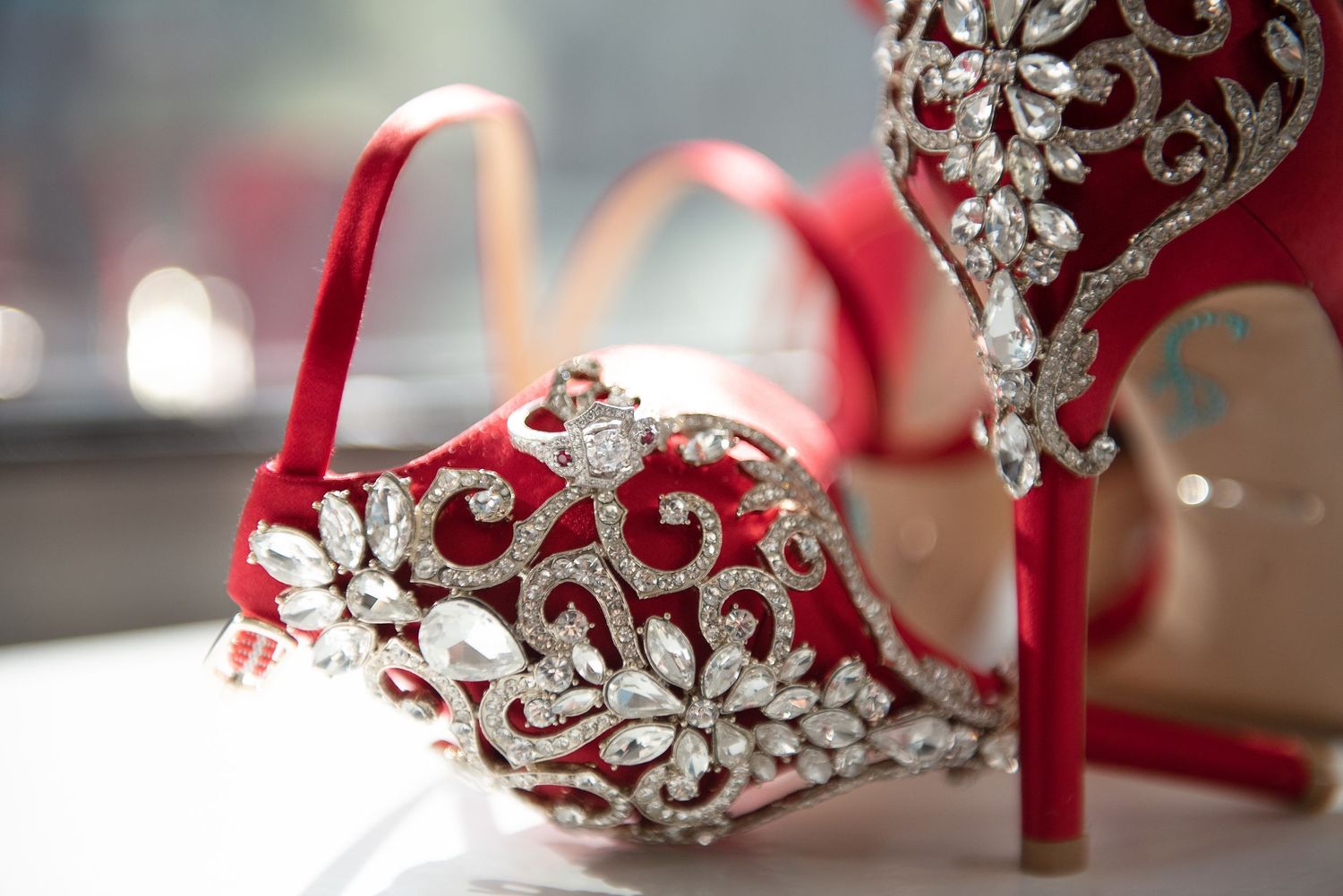 Elegant red satin wedding heels adorned with intricate silver crystal embellishments and floral details.
