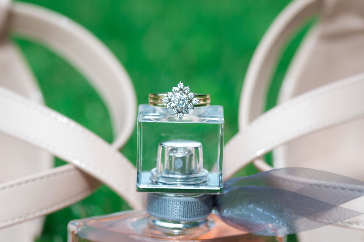 Diamond engagement ring and gold wedding band displayed on small glass box.