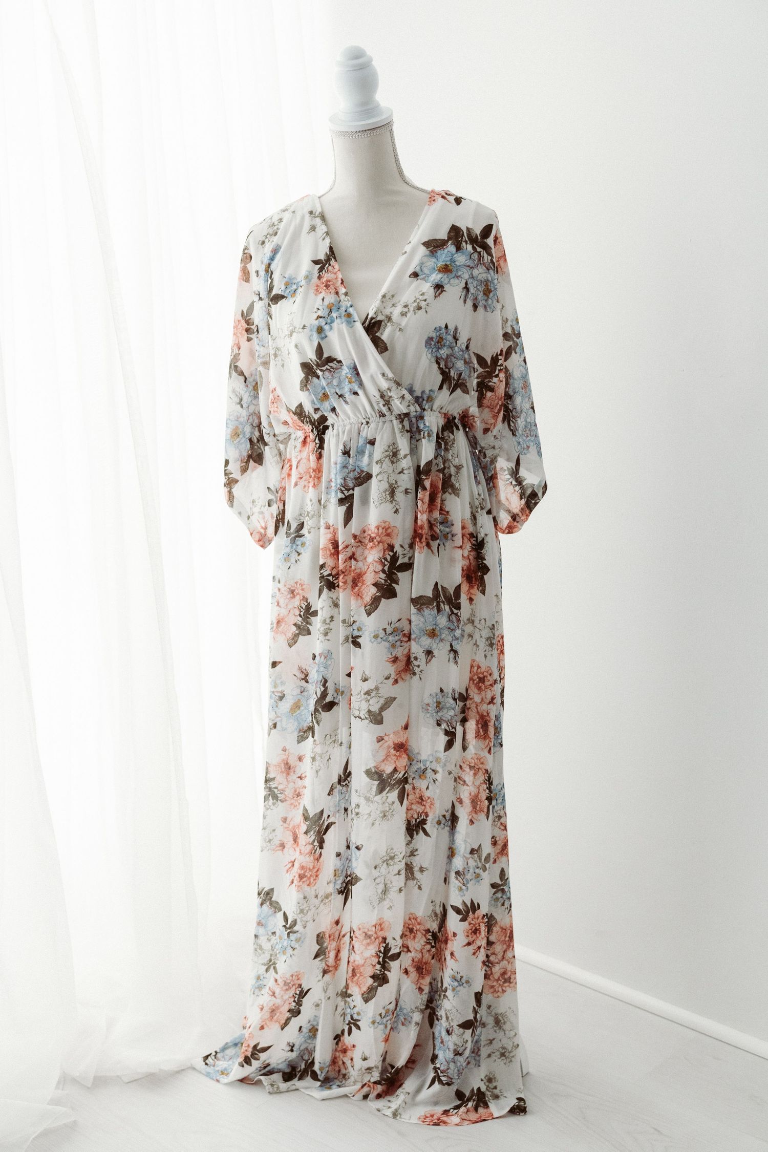 White floral chiffon maxi dress with wrap bodice and flutter sleeves on a mannequin.