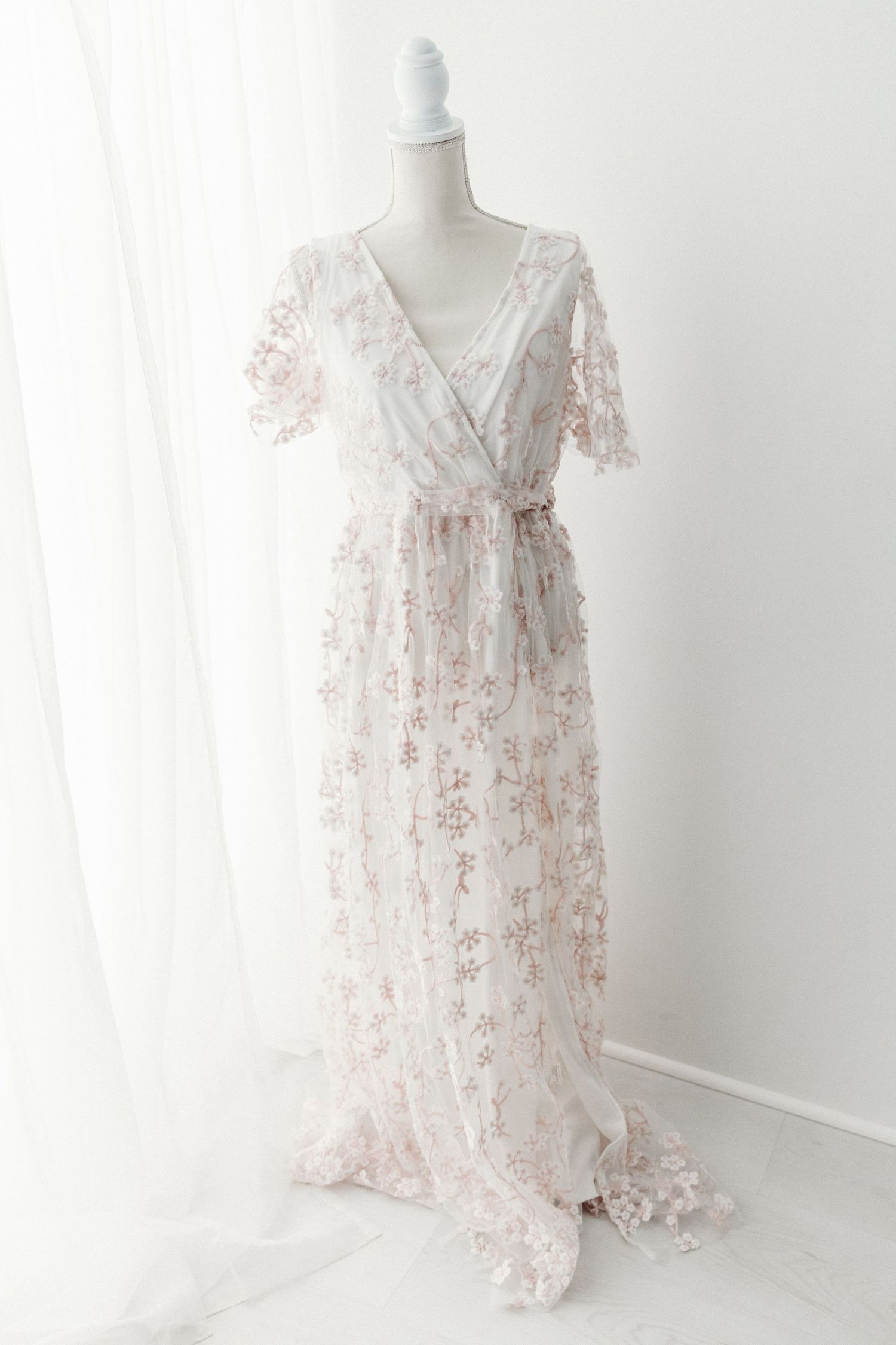 White floral lace V-neck short sleeve maxi dress with sash on mannequin.