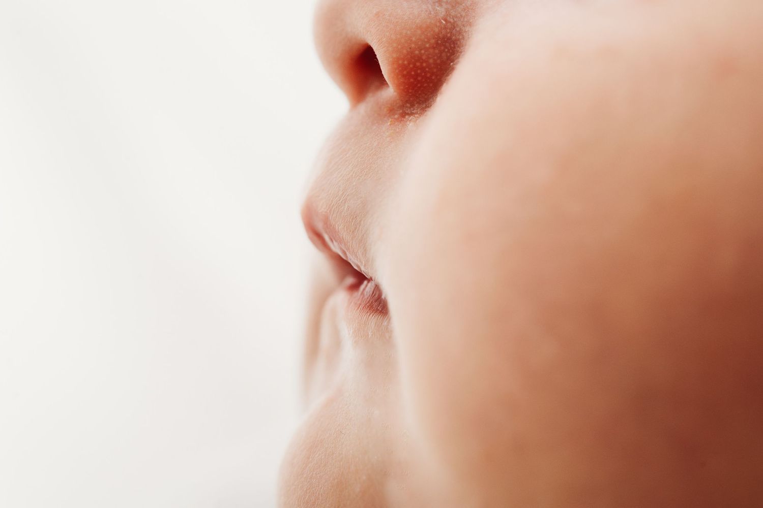 Close-up profile of a baby's nose and lips on a soft white background.