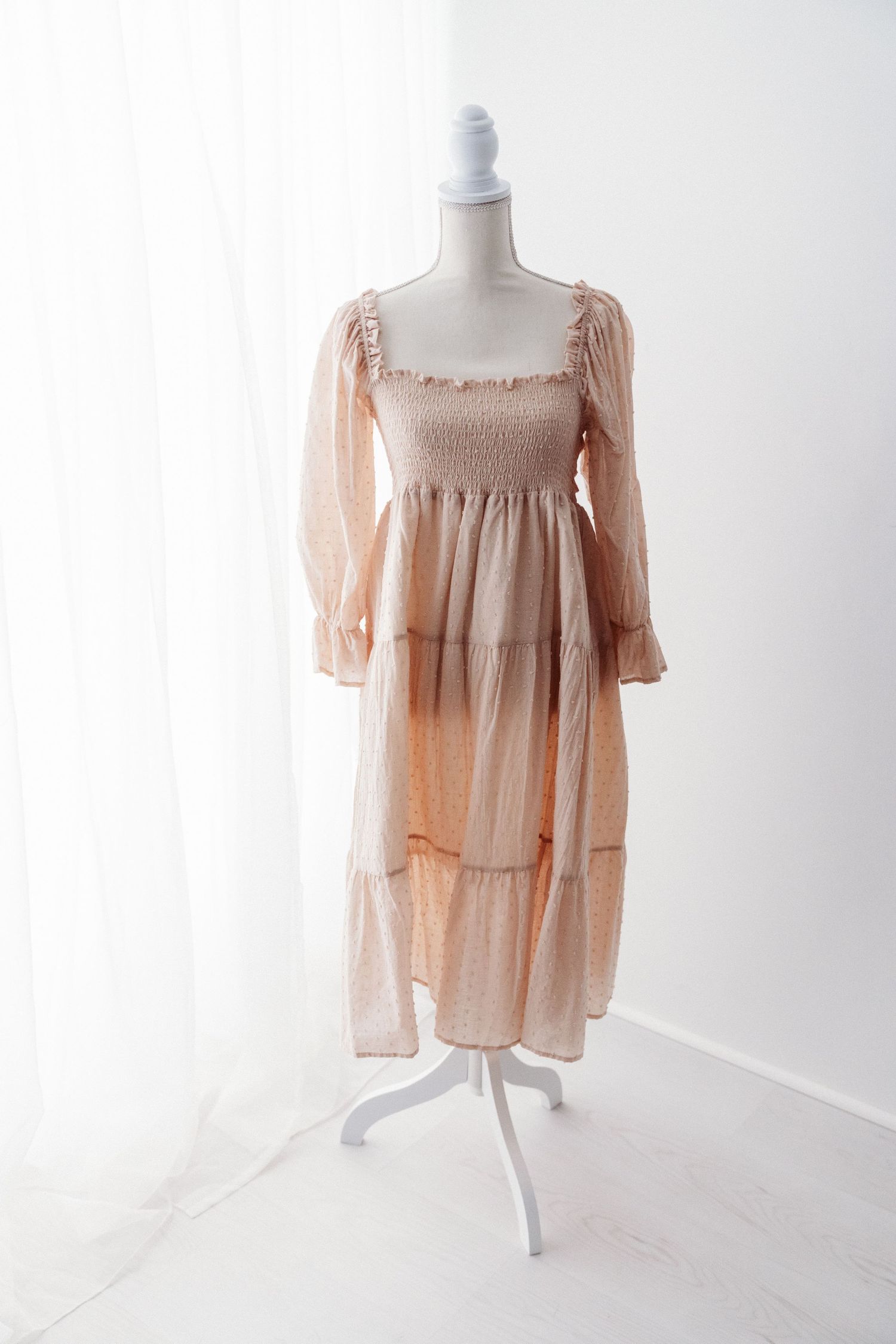 Light peach long sleeve smocked bodice tiered maxi dress displayed on mannequin.
