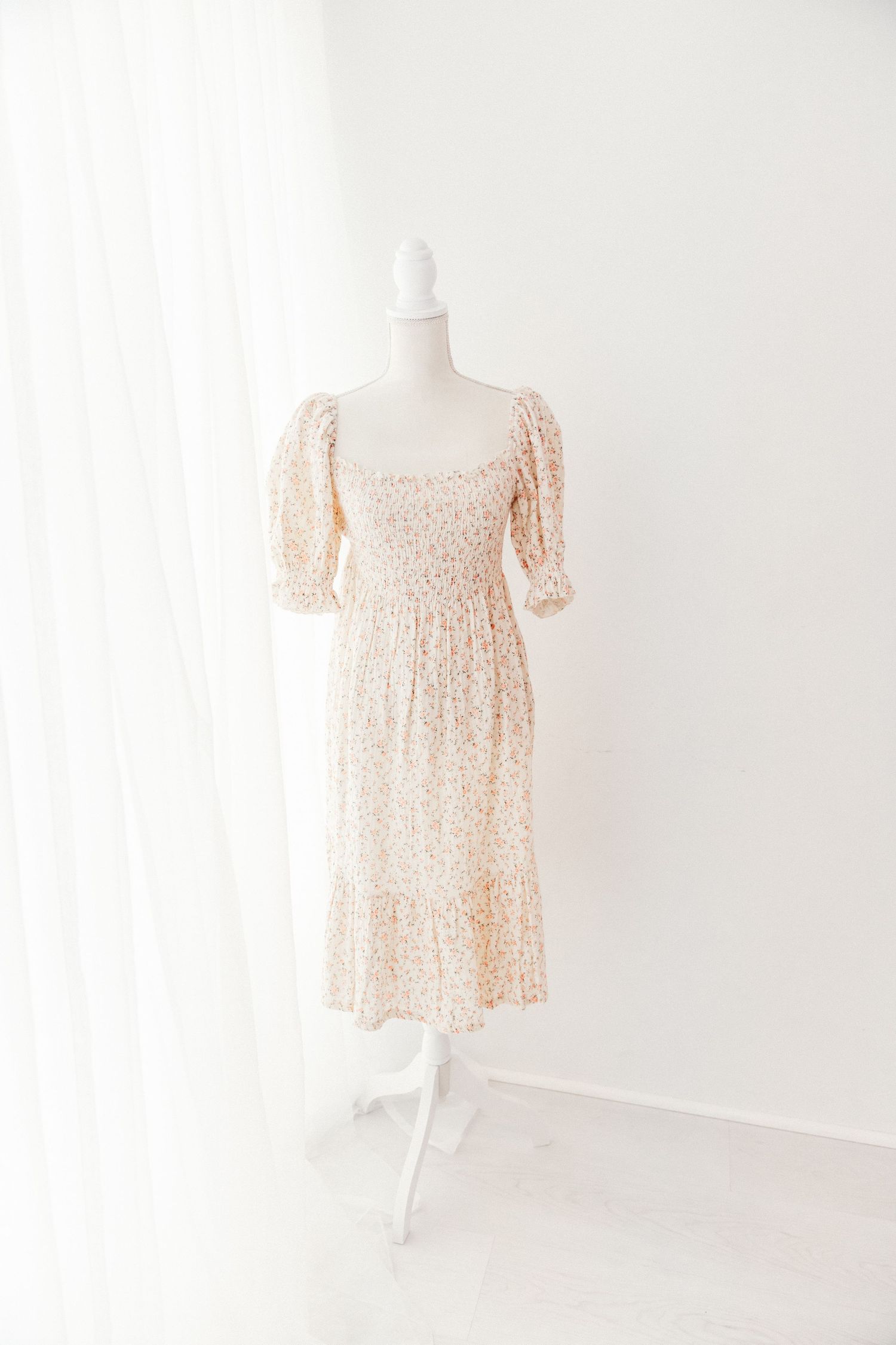 Floral puff sleeve midi dress with smocked bodice and tiered skirt on mannequin.