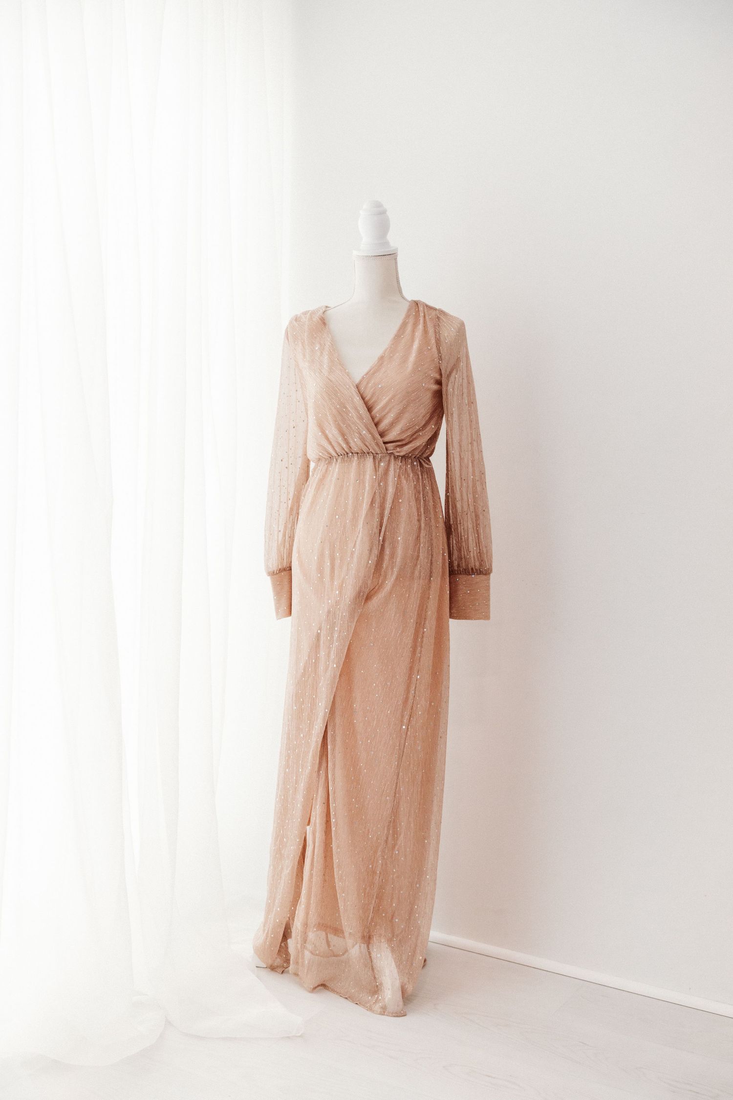Elegant gold wrap maxi dress with long sleeves on a mannequin.